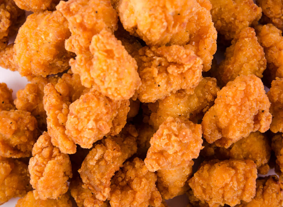 A Pile Of Fried Chicken Nuggets On A White Surface Wallpaper