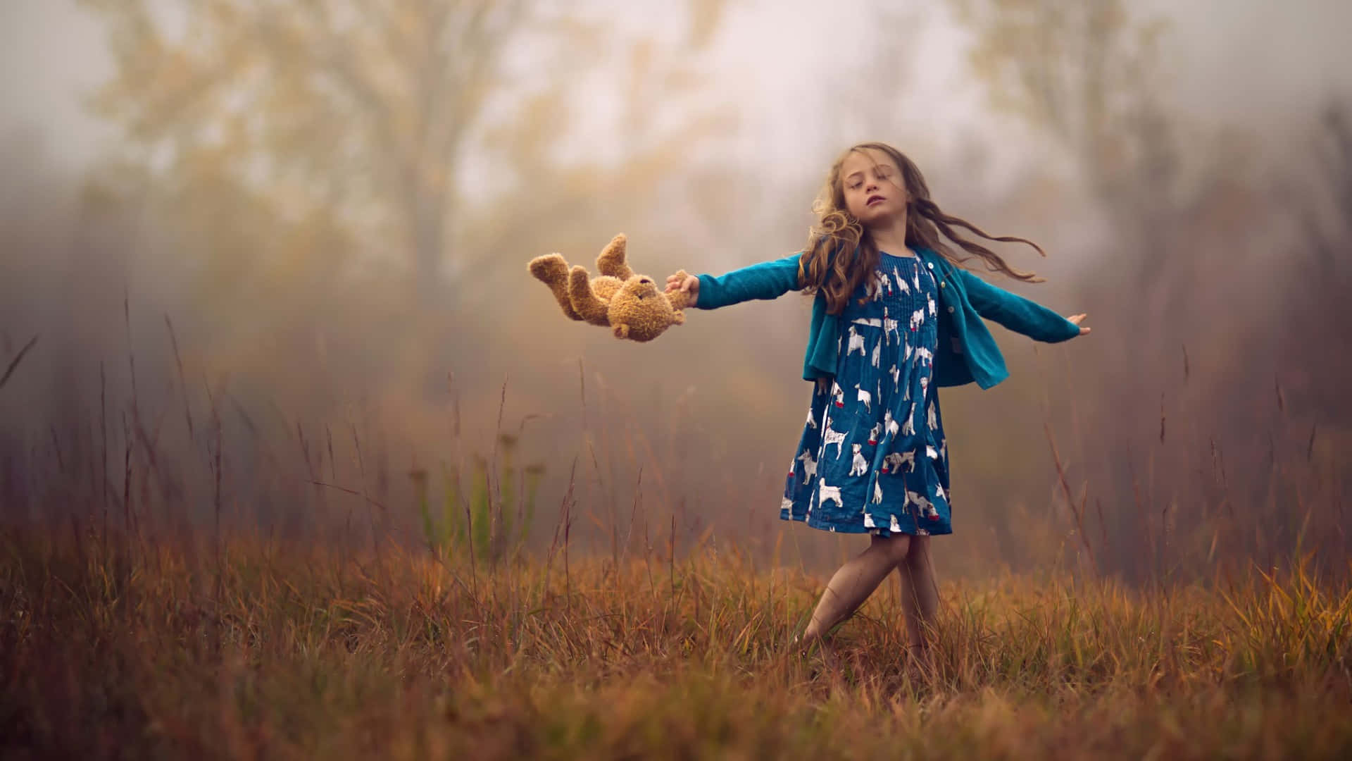 A Girl Is Holding A Teddy Bear In A Field