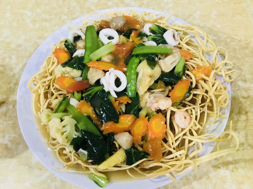 A Plate Of Noodles With Vegetables And Seafood On It