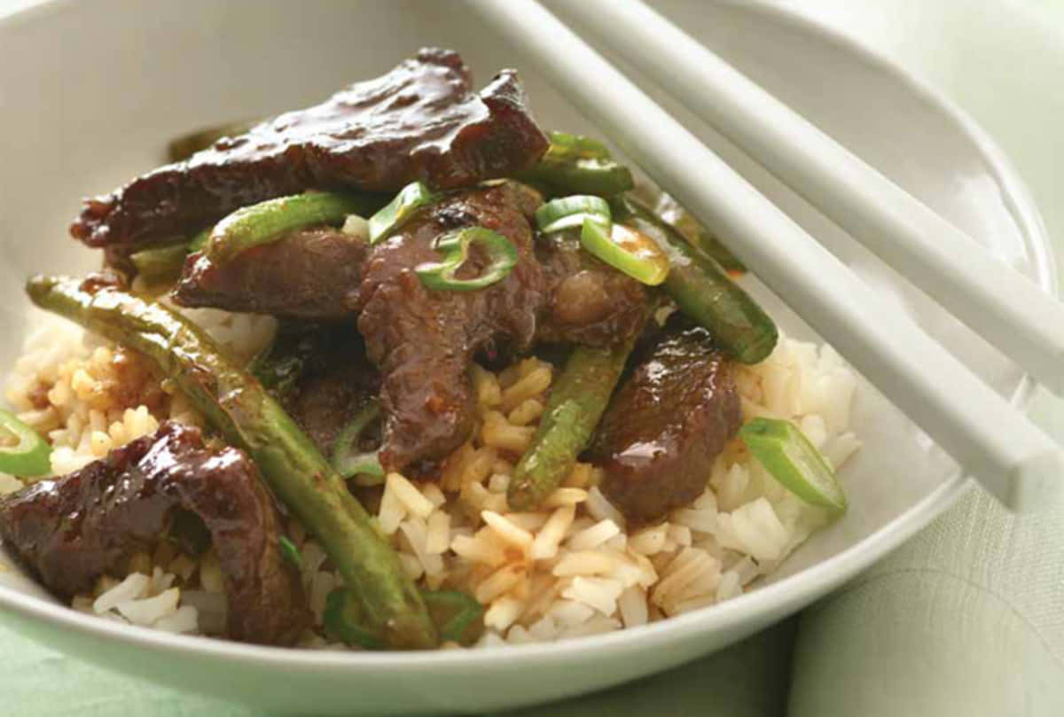 A Bowl Of Beef And Green Beans With Chopsticks
