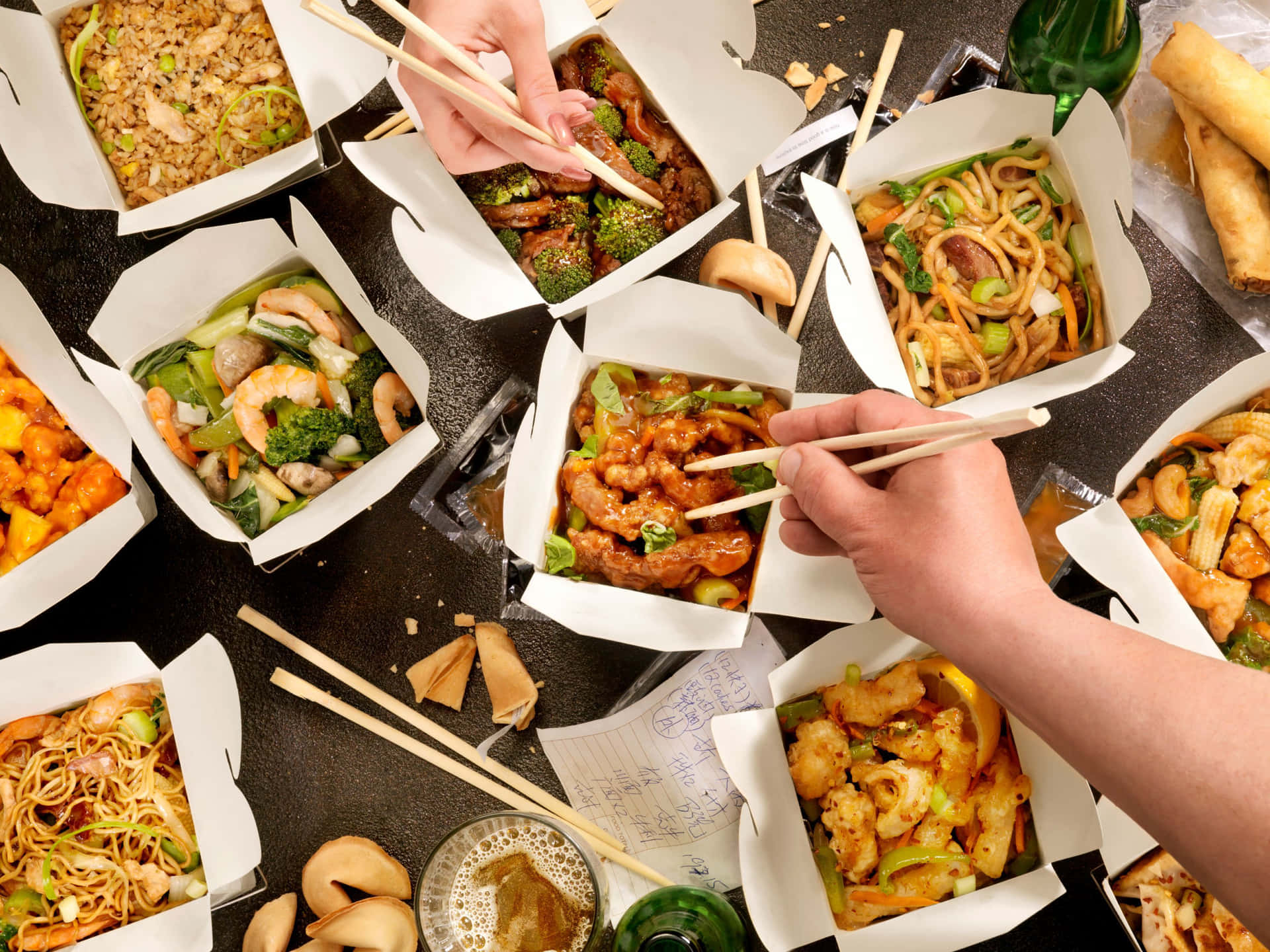A Group Of People Holding Chopsticks And Eating Asian Food