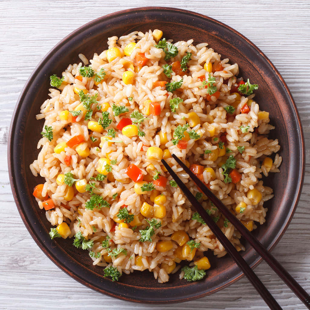 A Plate Of Rice With Vegetables And Chopsticks