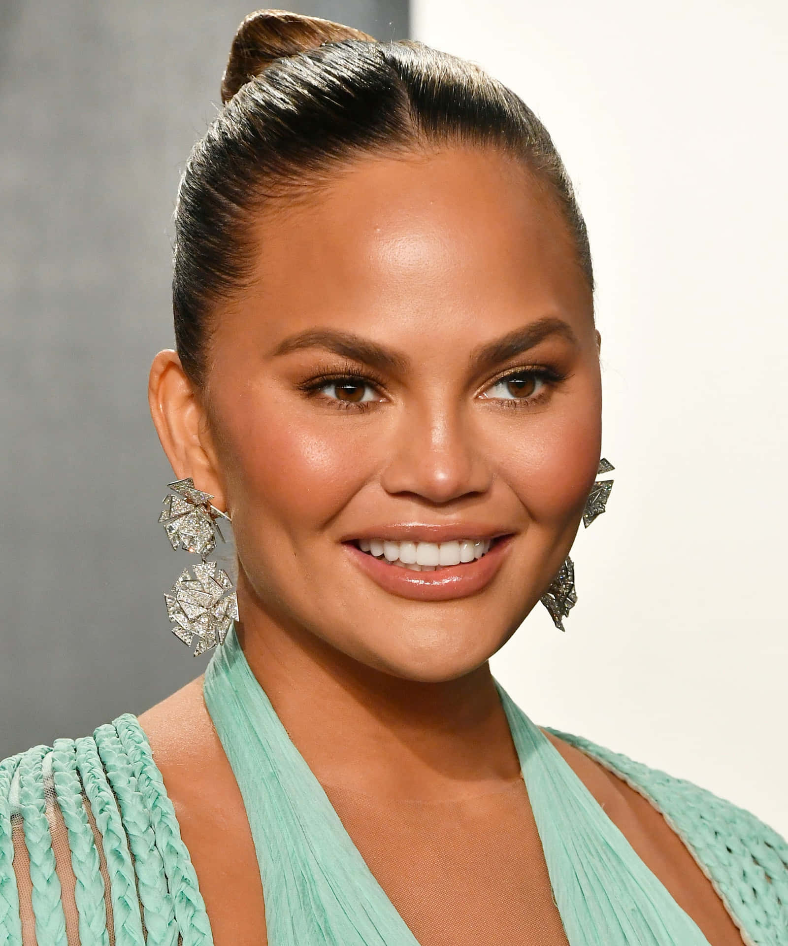 Download Chrissy Teigen Smiling Portraitwith Earrings Wallpaper ...