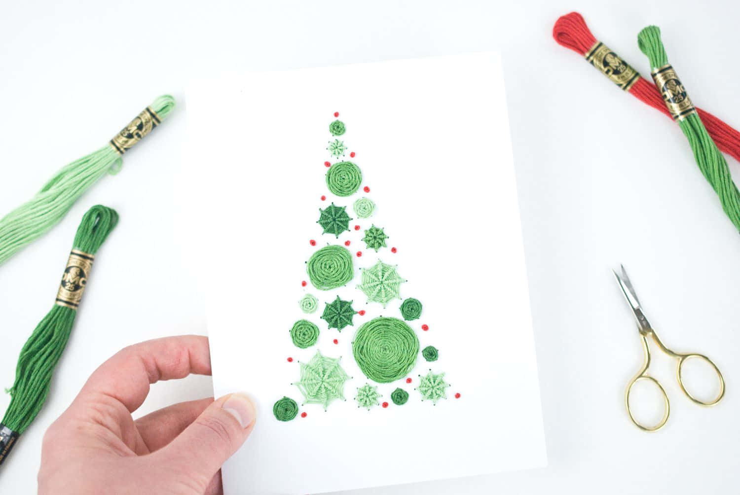 Eineperson Hält Eine Weihnachtskarte Mit Grünen Und Roten Pompons.