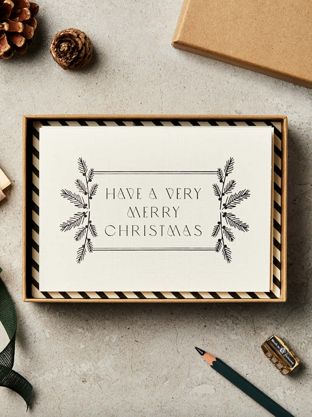 Umacaixa Com Um Cartão De Natal E Um Cone De Pinheiro.