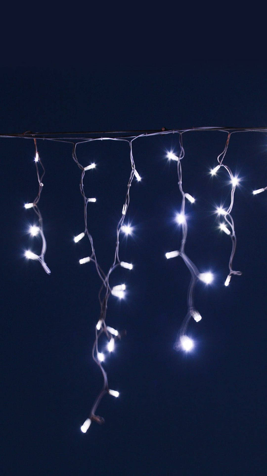 White Led String Lights Hanging From A Wire Wallpaper
