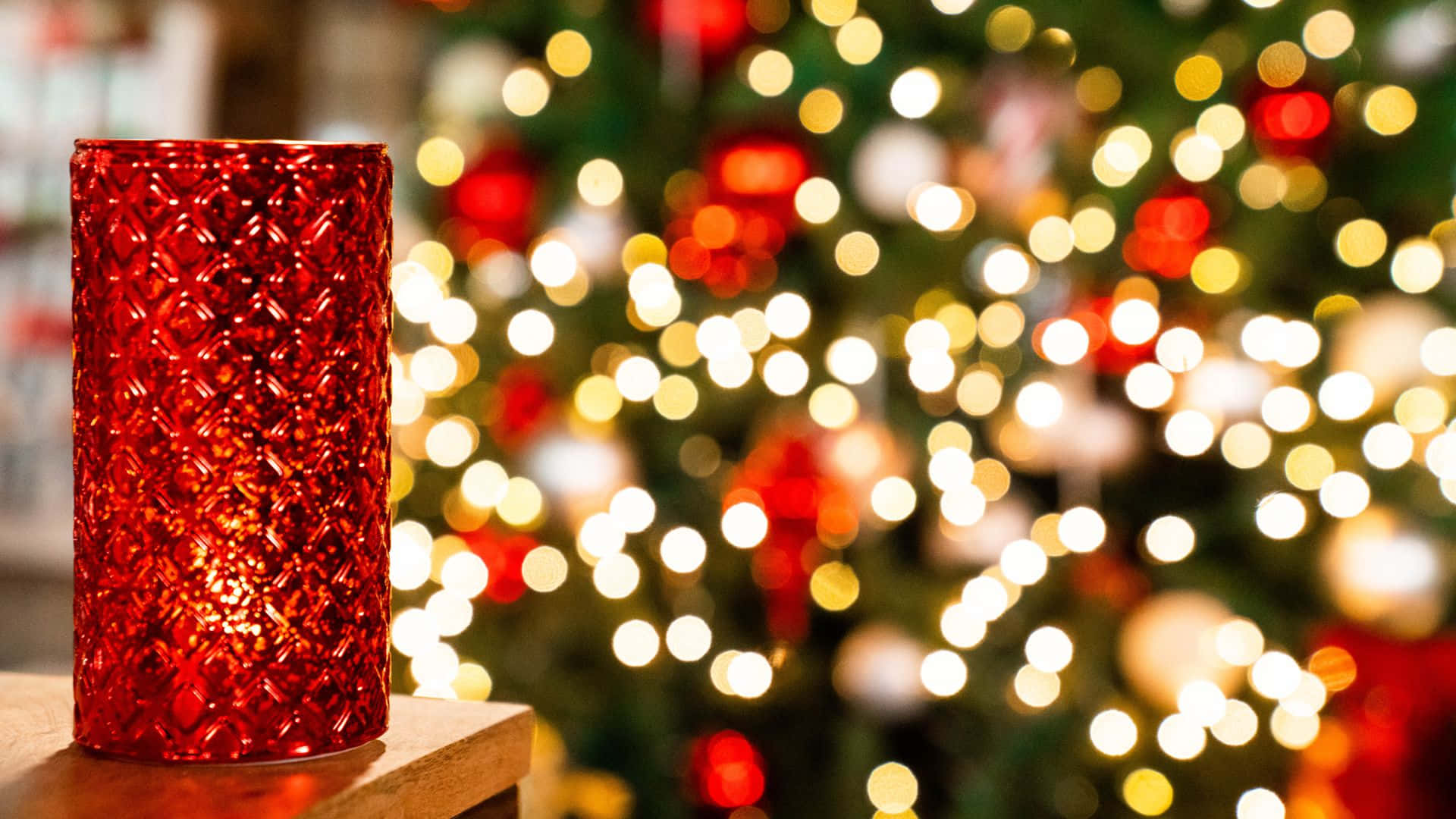 Umavela Vermelha Está Sobre Uma Mesa, Em Frente A Uma Árvore De Natal.