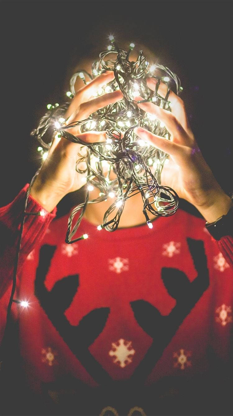 A Person Holding Up A Christmas Light Wallpaper