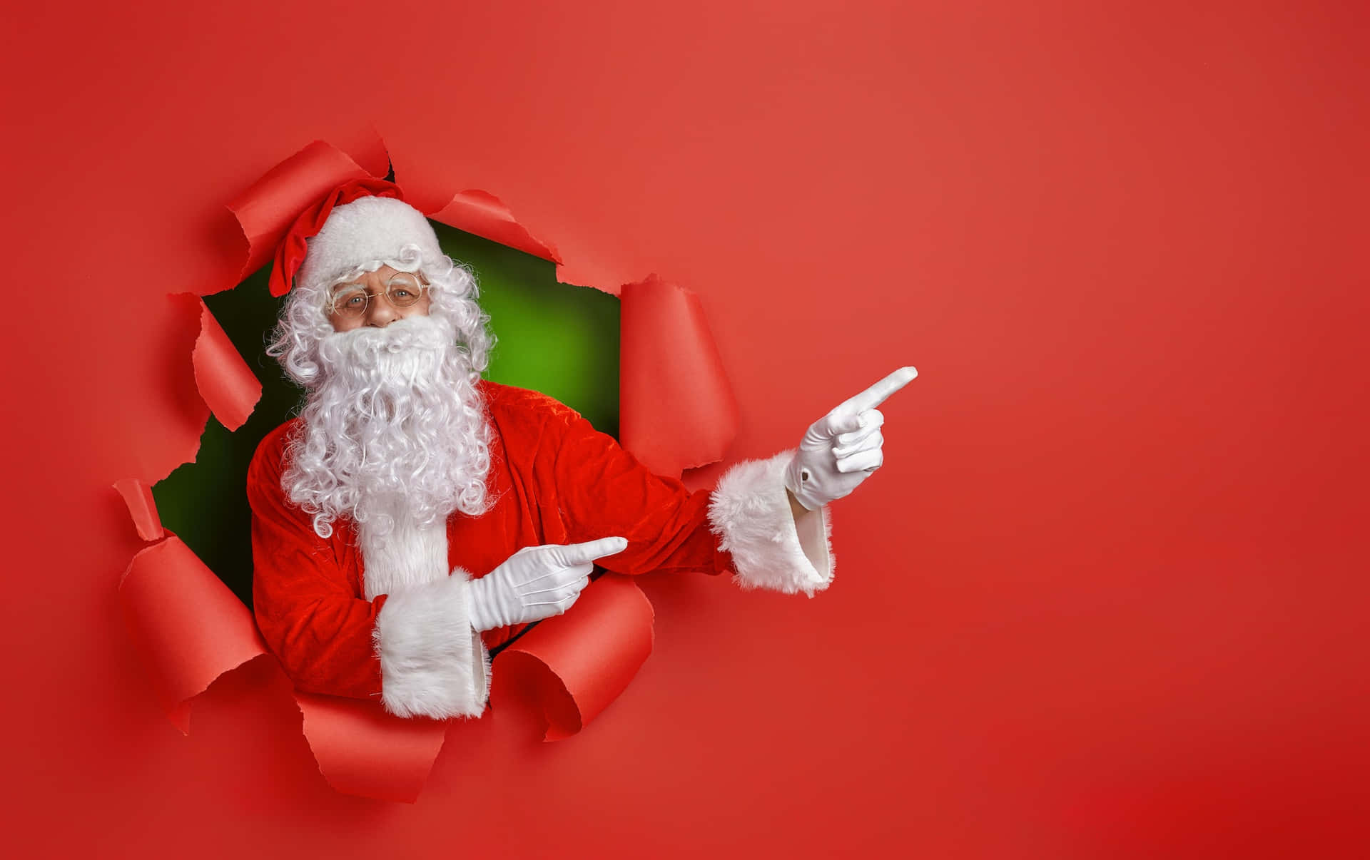 Santa Claus Pointing Out Of A Hole In A Red Background