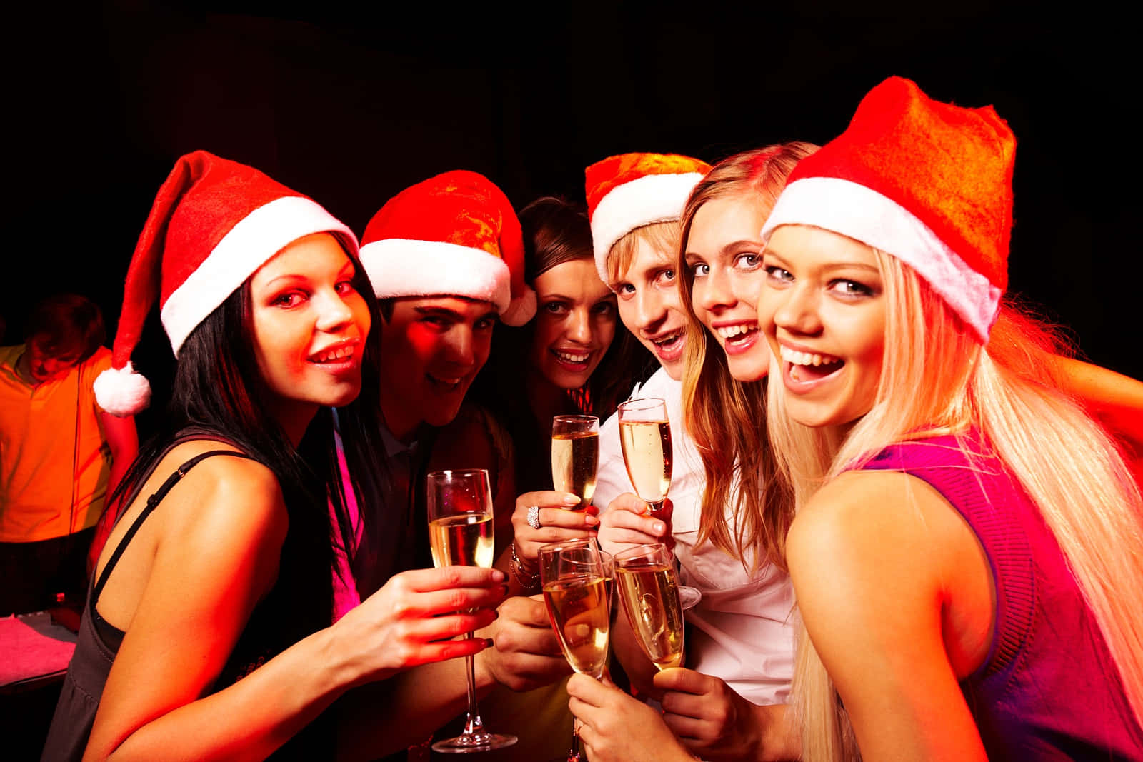A Group Of Women In Santa Hats Holding Champagne Glasses