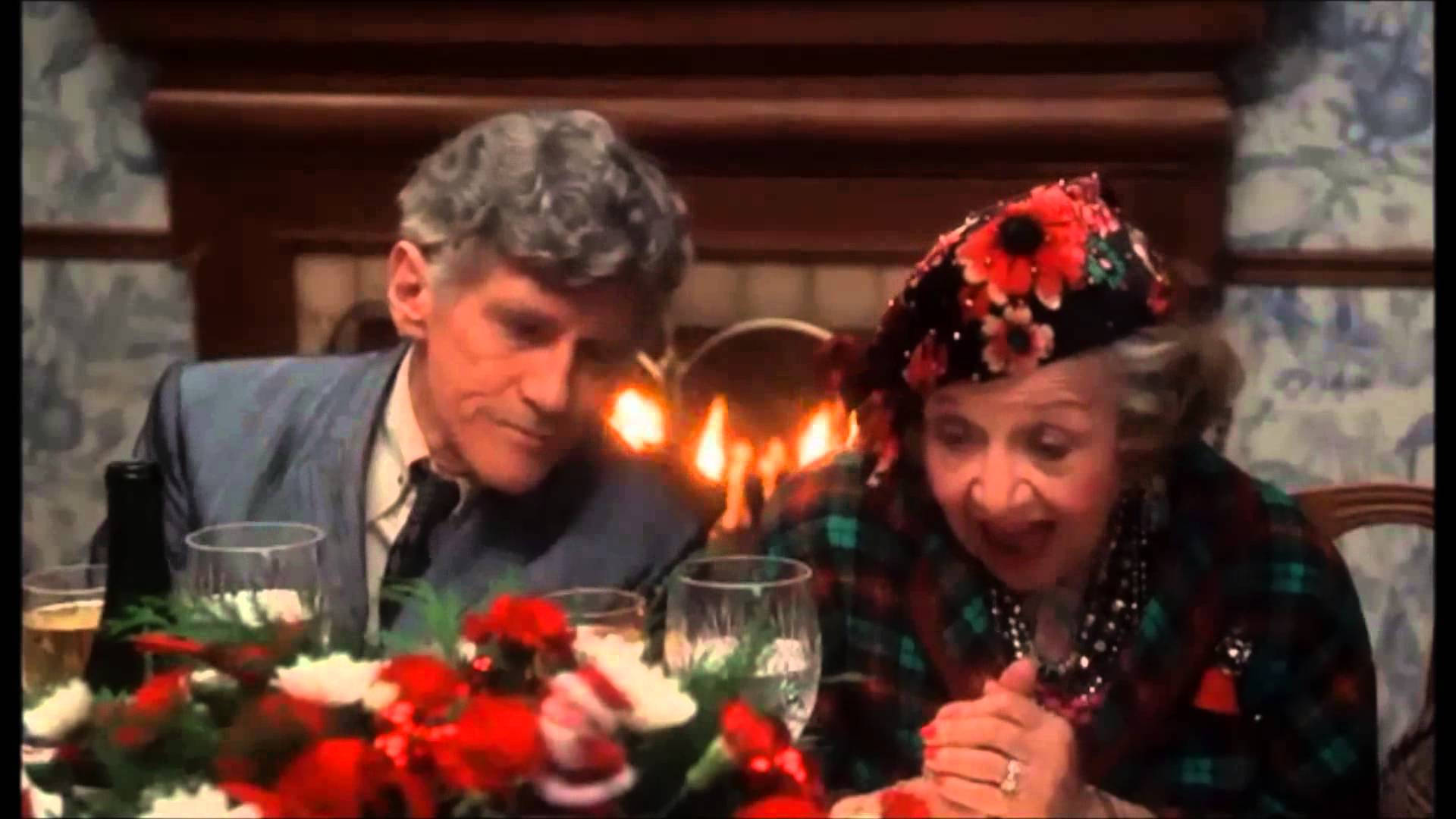 A Man And Woman Sitting At A Table With A Christmas Tree Wallpaper