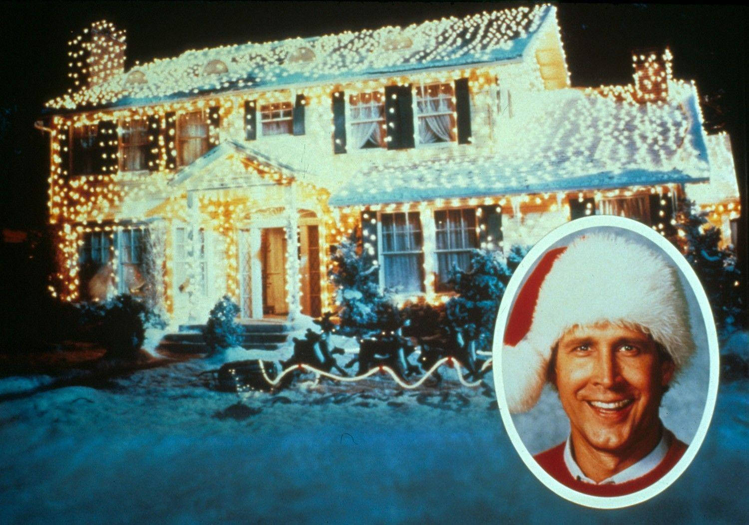 En mand iført julehue står foran et hus med lys. Wallpaper