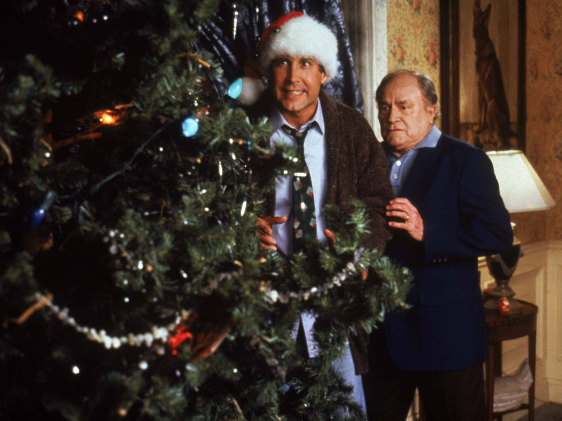 Two Men Standing Next To A Christmas Tree Wallpaper