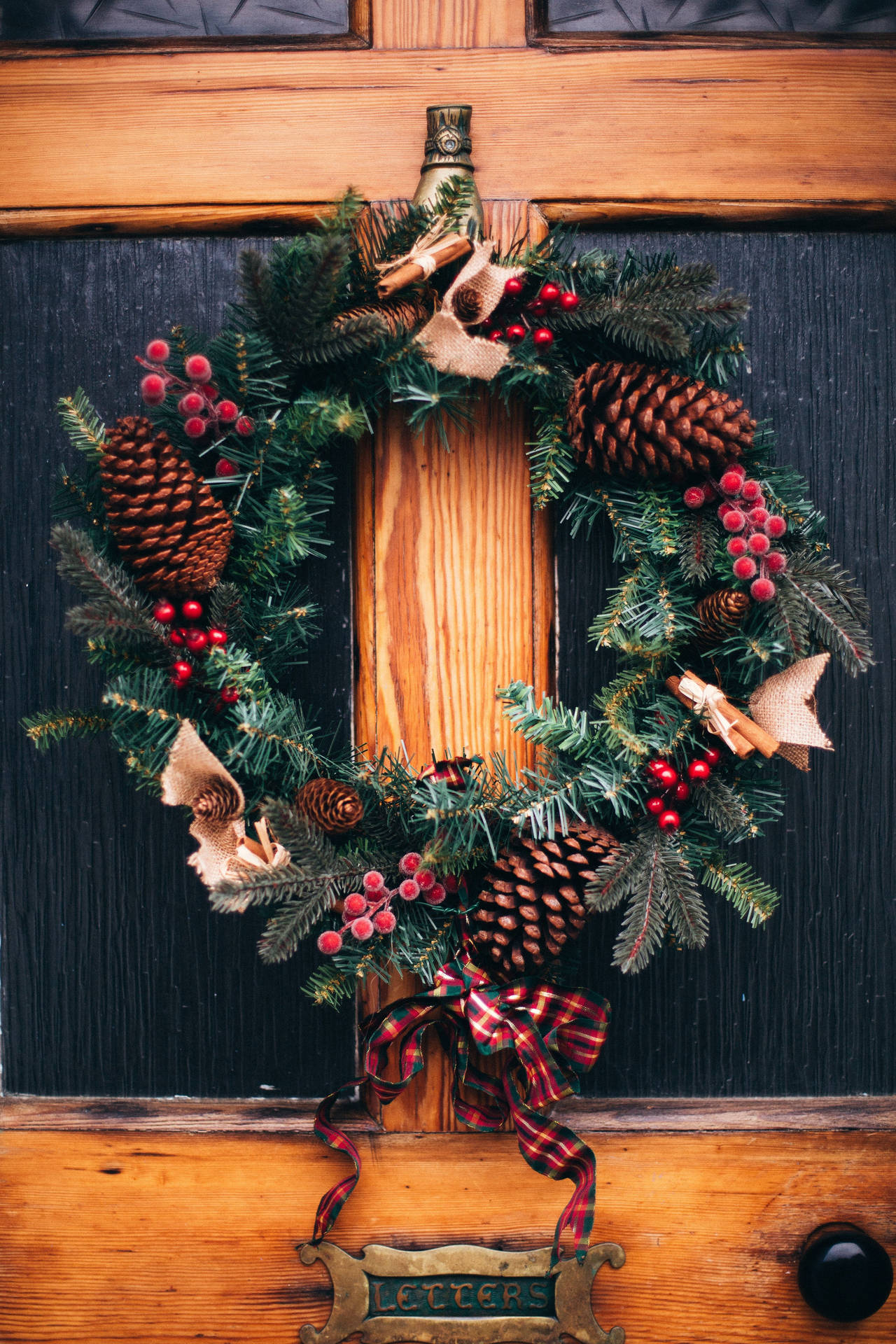 Christmas Wreath Embellished with Pinecones and Berries Wallpaper