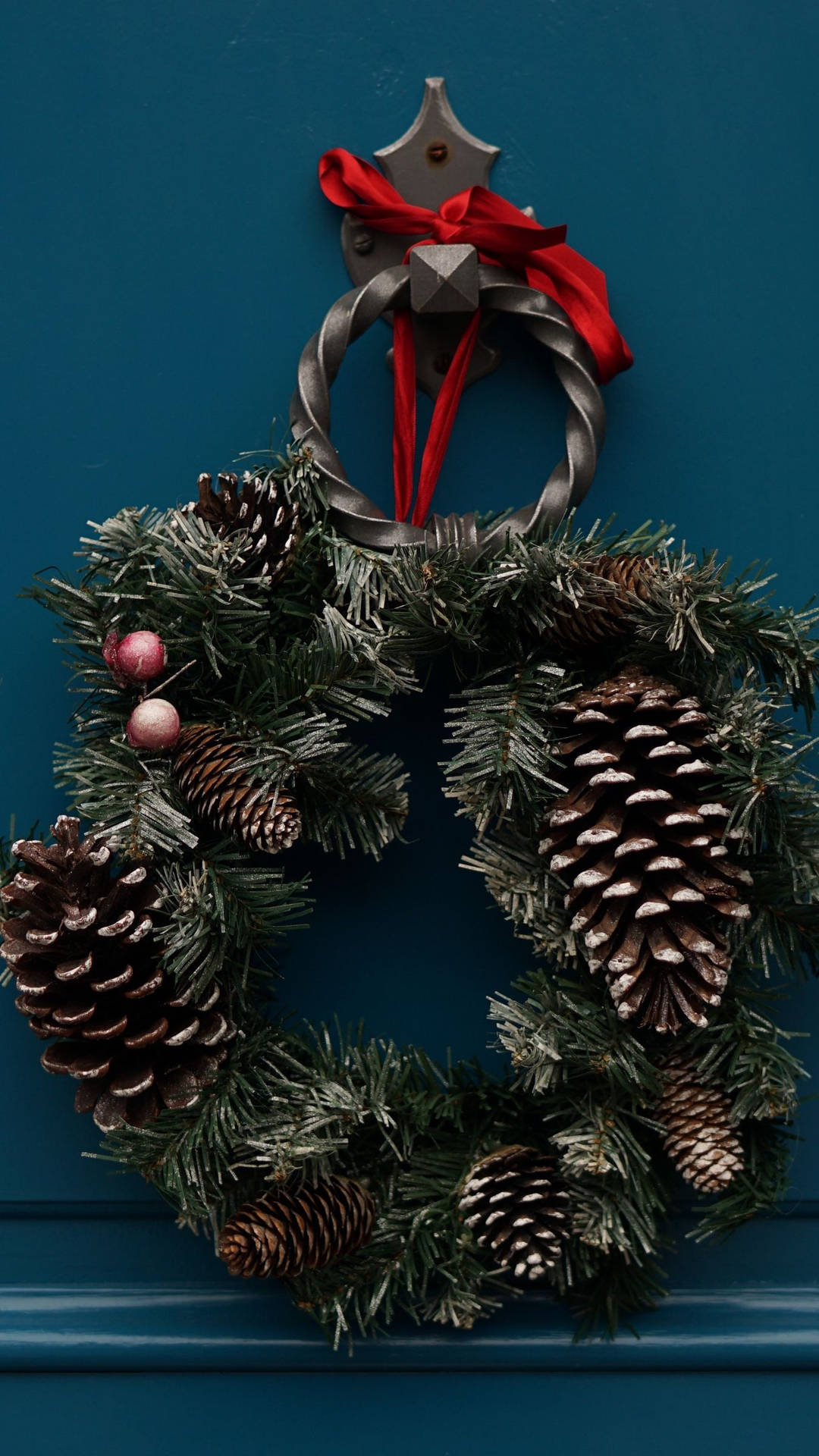 Caption: Festive Christmas Wreath Embellished with Pinecones Wallpaper