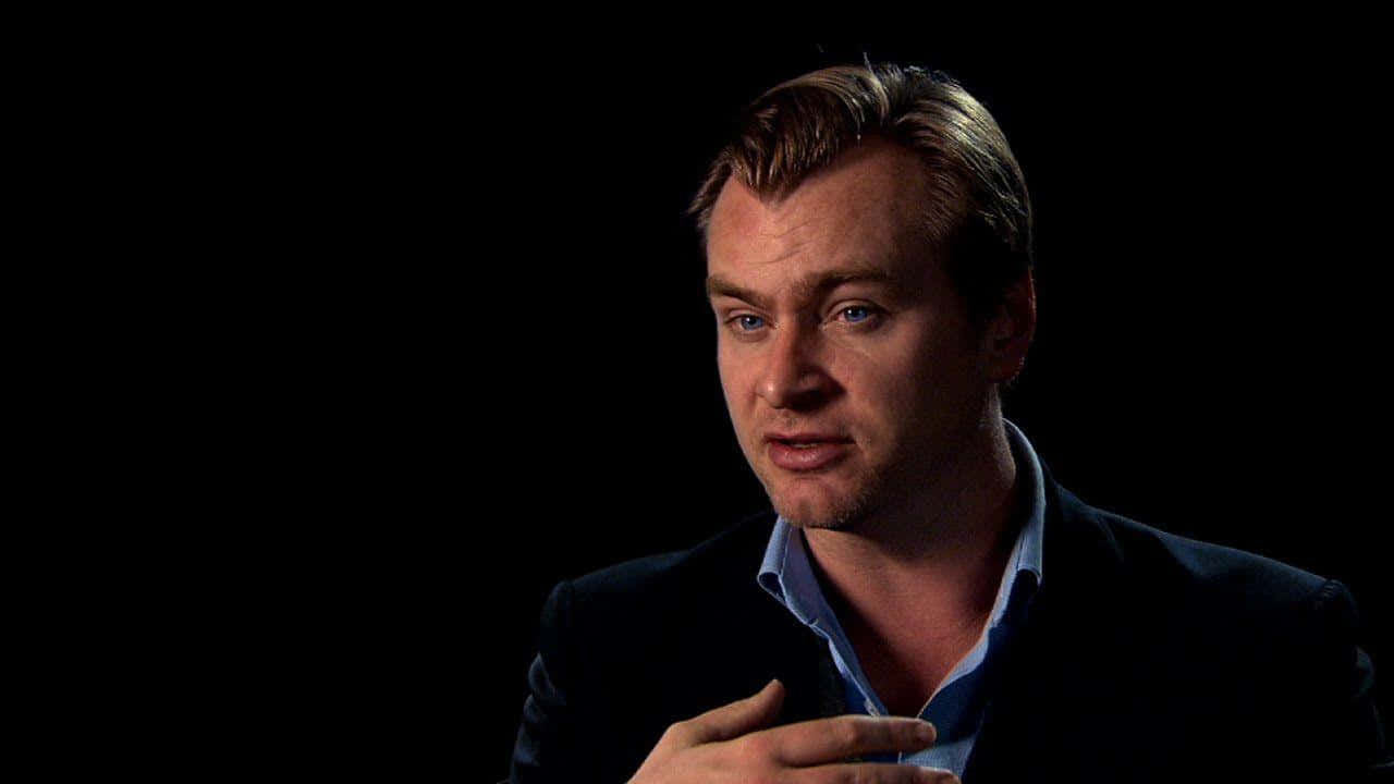 Christopher Nolan engaging in a conversation on set Wallpaper