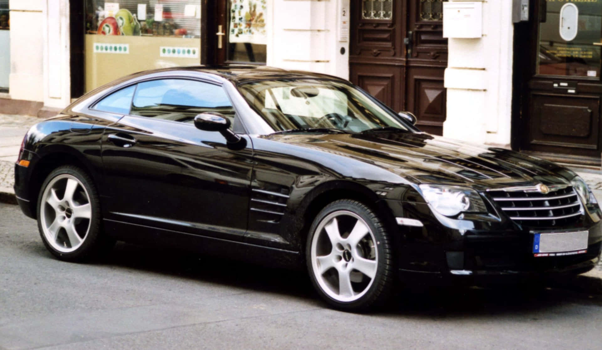 A Sleek Black Chrysler Crossfire on a Picturesque Highway Wallpaper