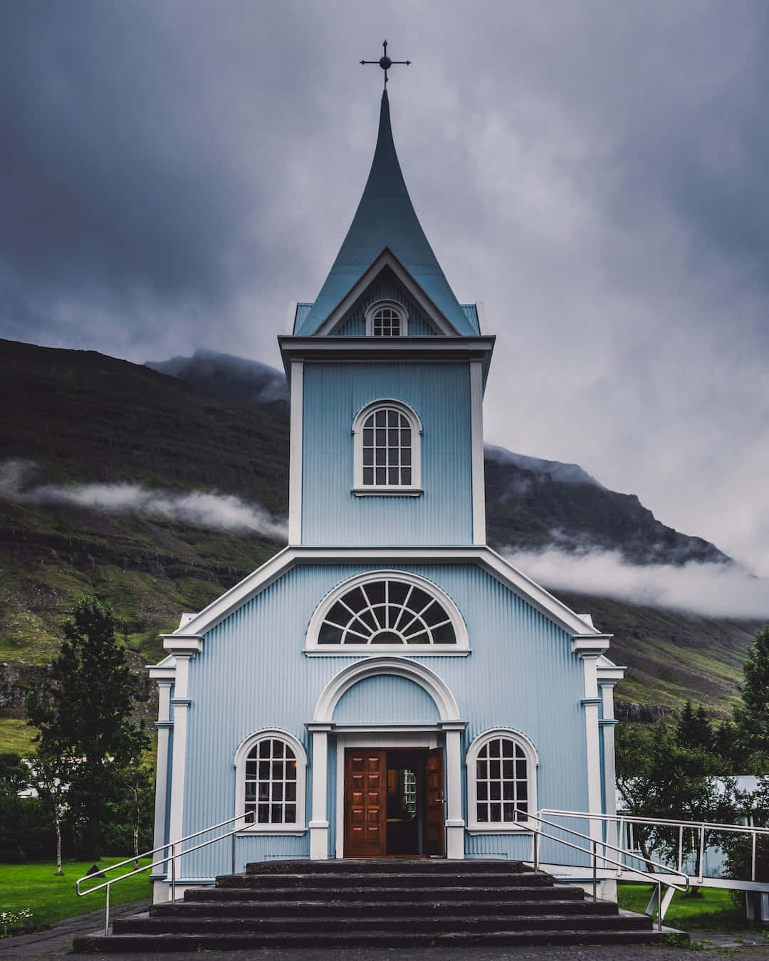 A Blue Church In Front Of A Mountain