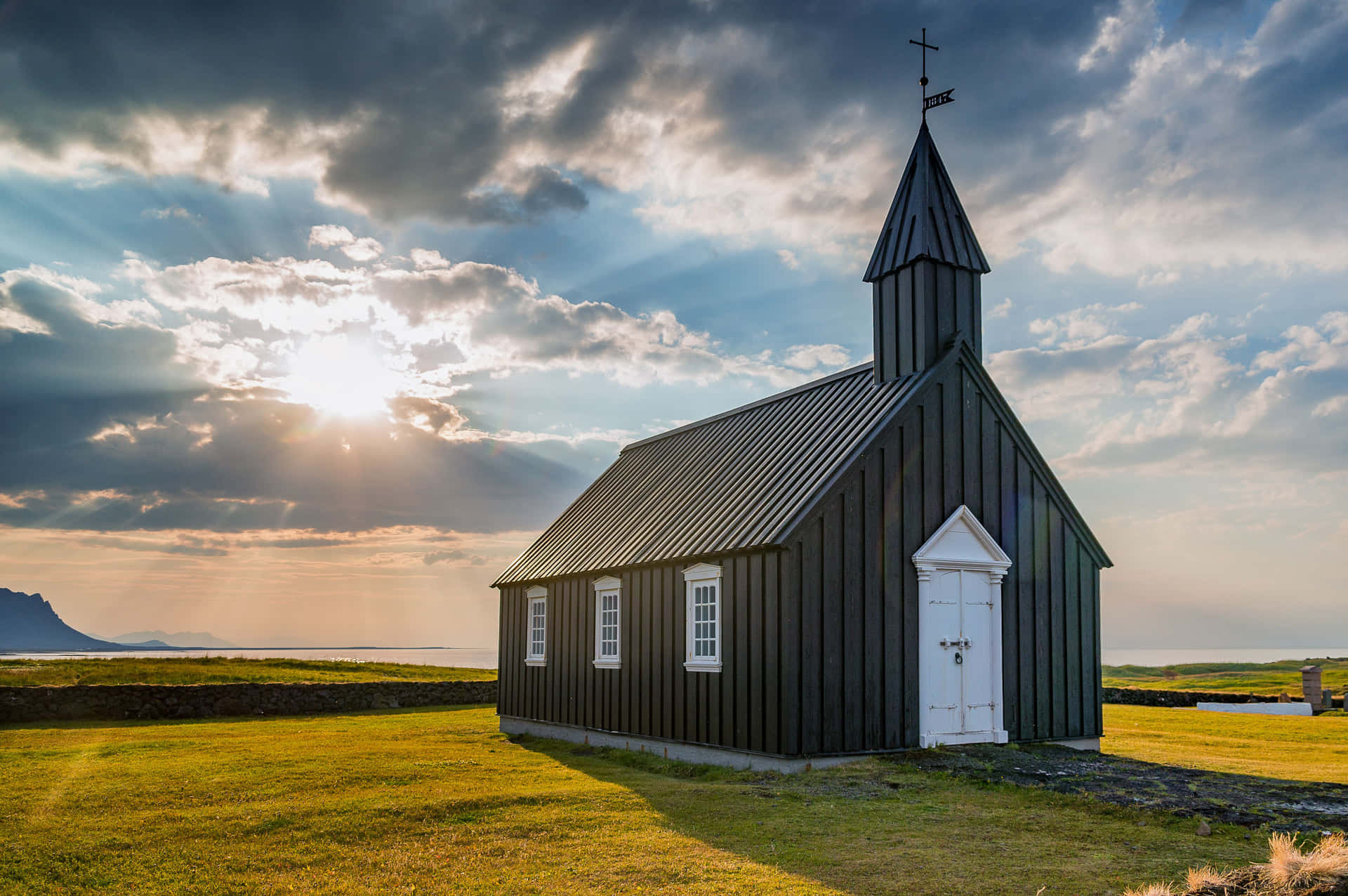 A Black Church Sits On A Grassy Field