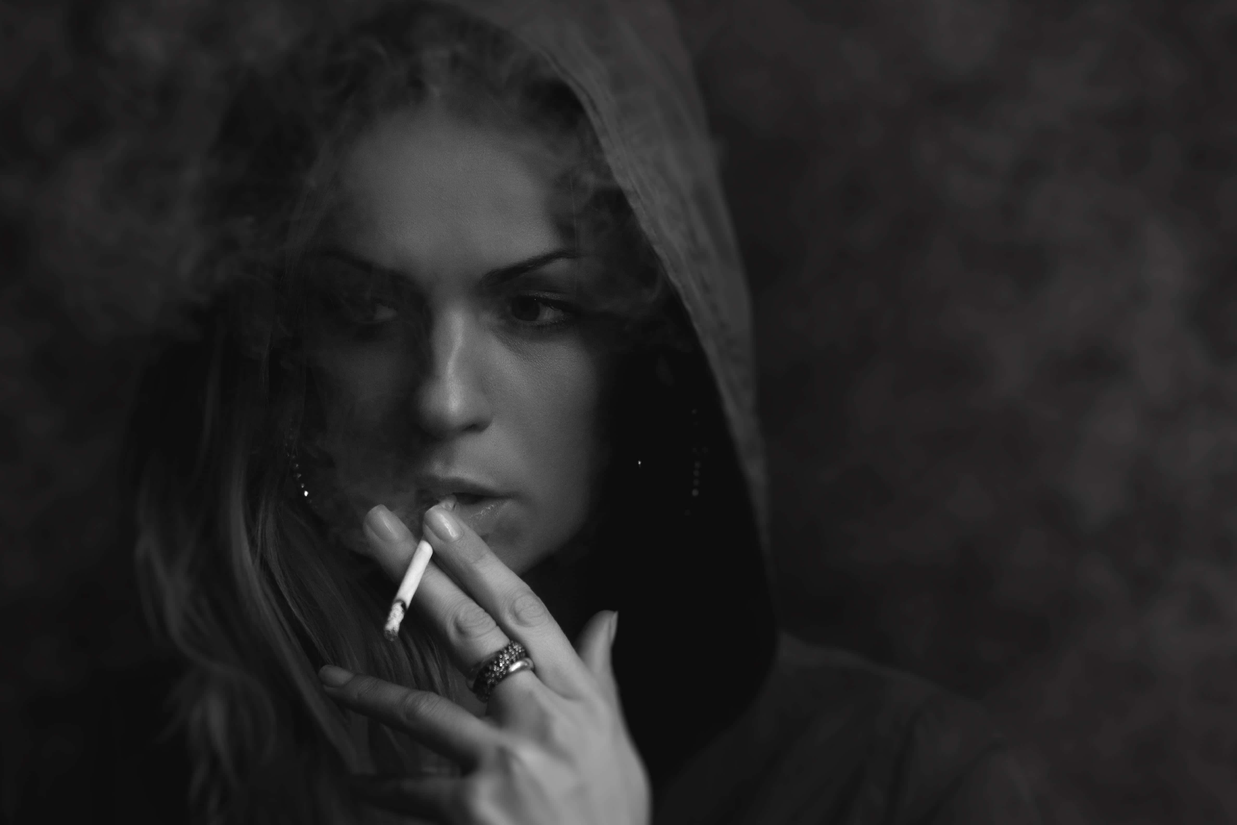 Kvinde med hoodie ryger cigaret billede tapet