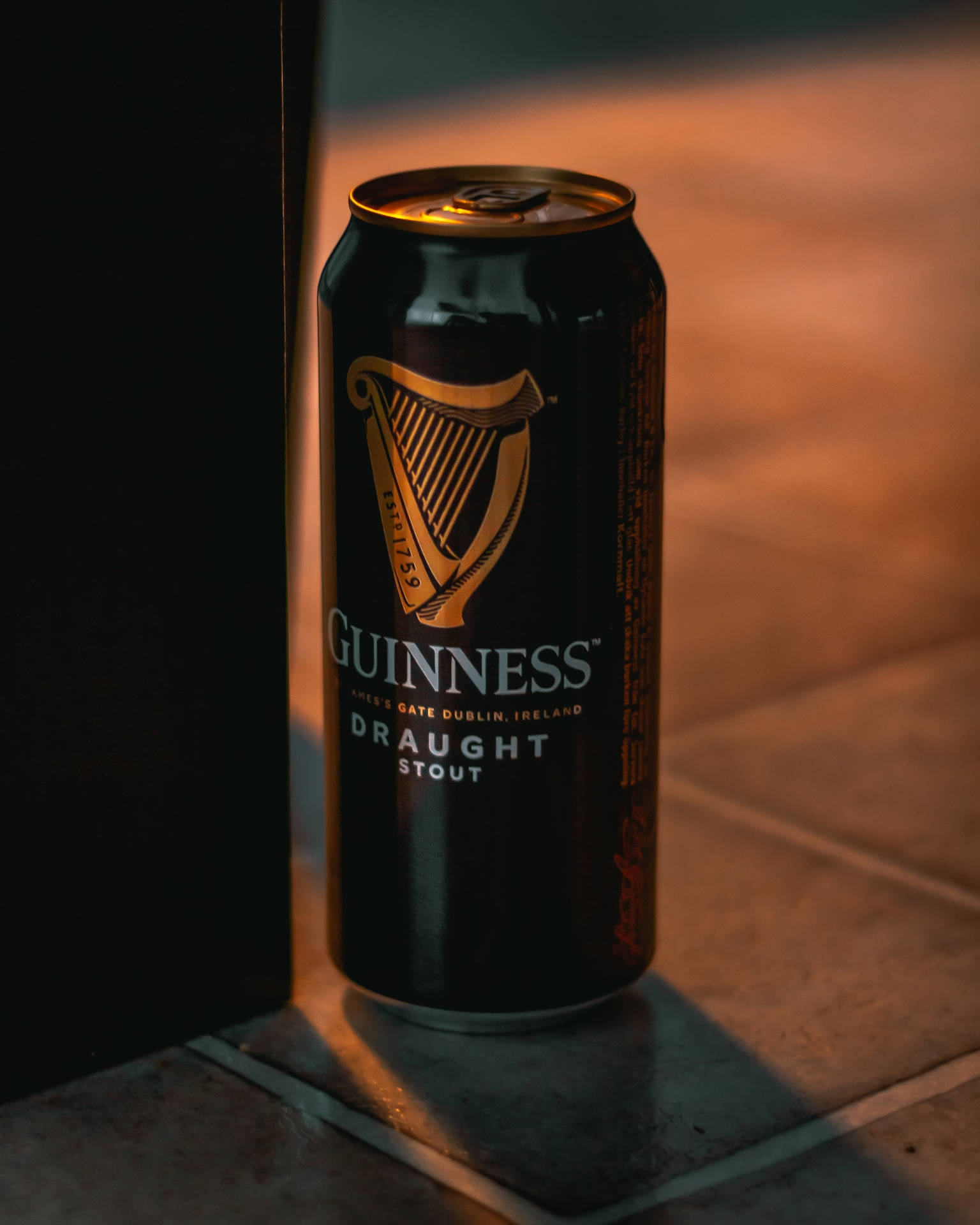 Caption: Refreshing Guinness Stout Can on a Cinematic Background Wallpaper
