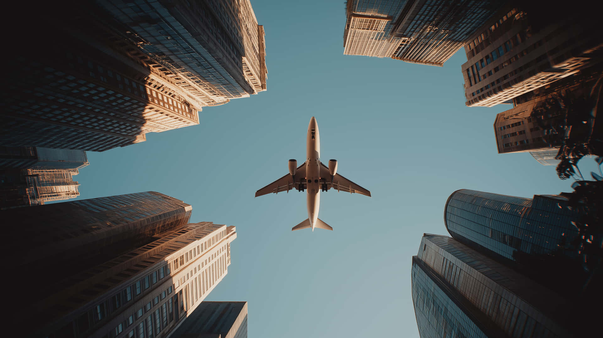 Cinematic View Of A Plane Soaring Between Towering City Skyscrapers Wallpaper