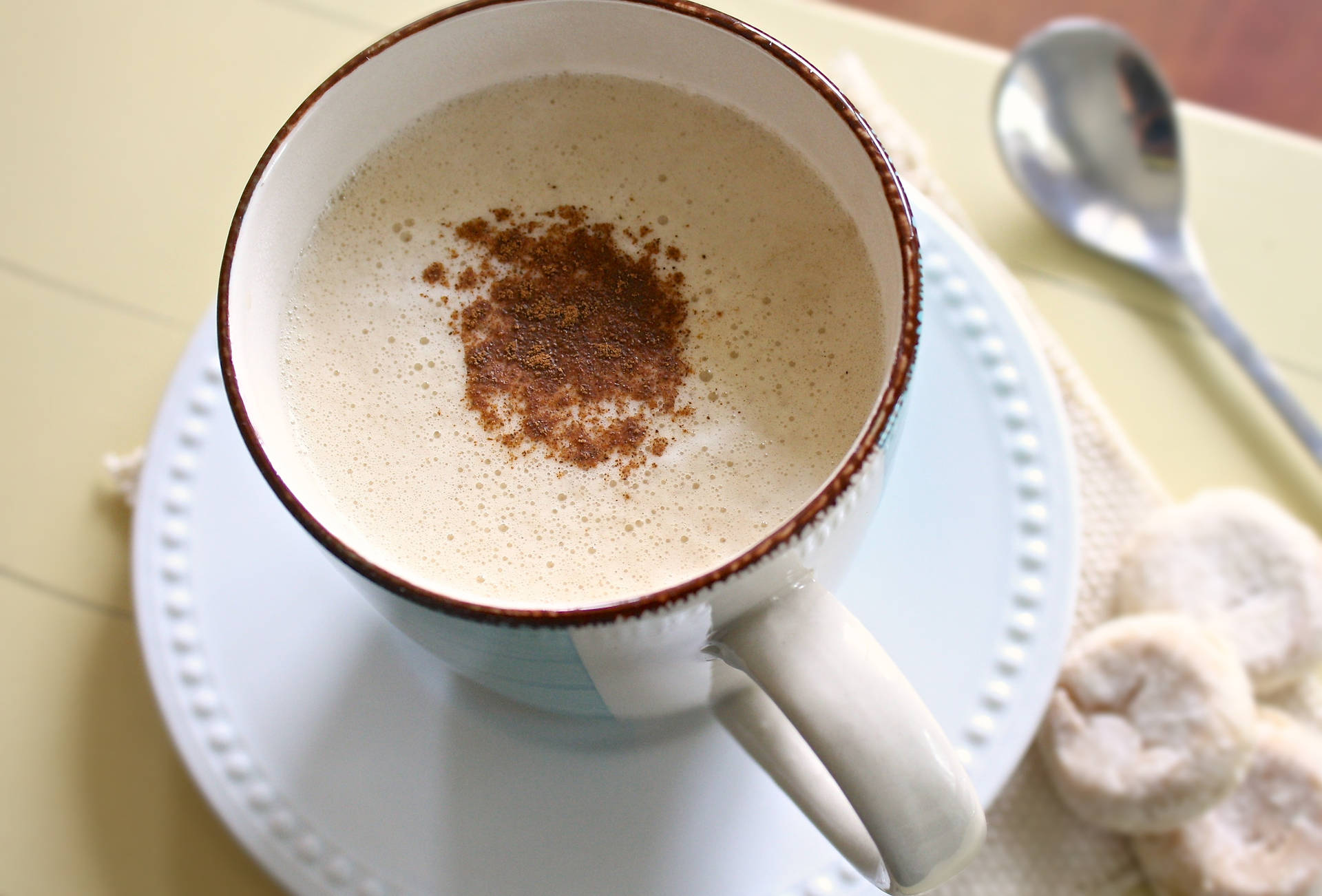 A steaming cup of freshly brewed cinnamon-flavored coffee with a creamy layer of foam Wallpaper