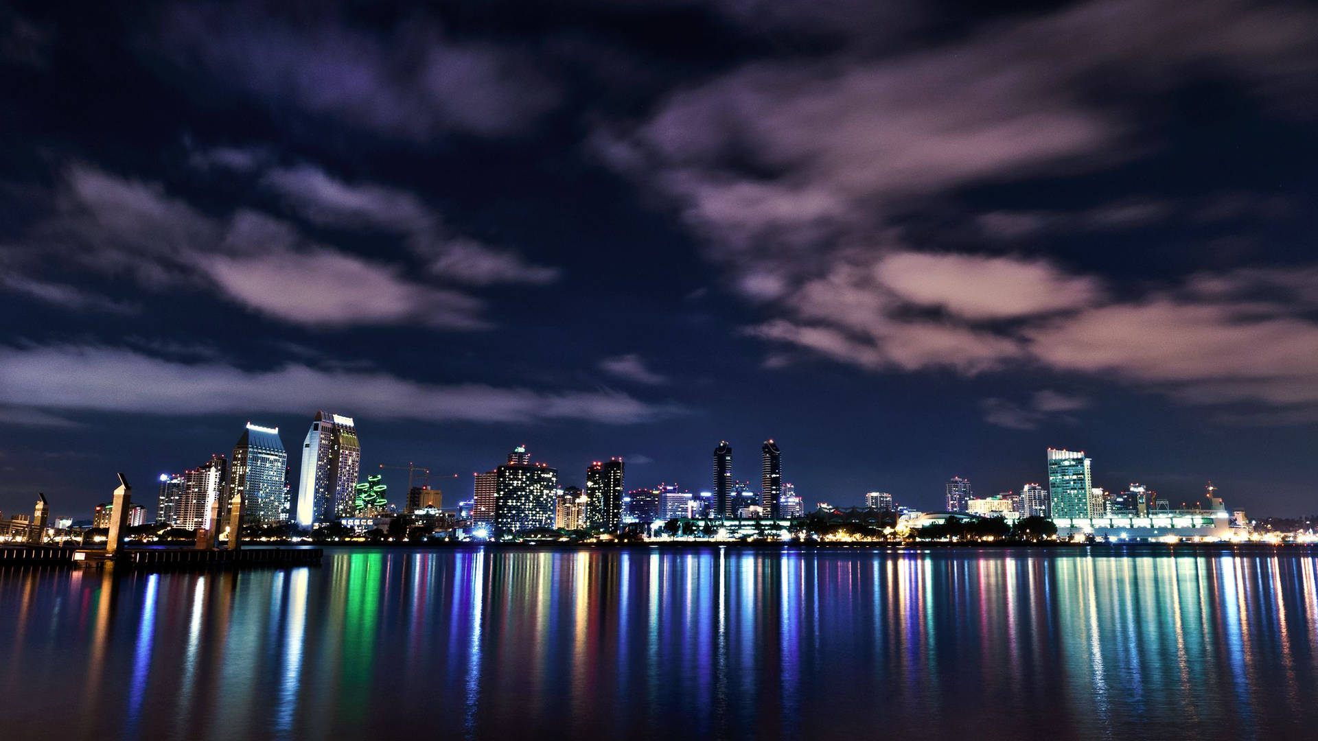 Night view of a city skyline silhouetted against a calm river Wallpaper
