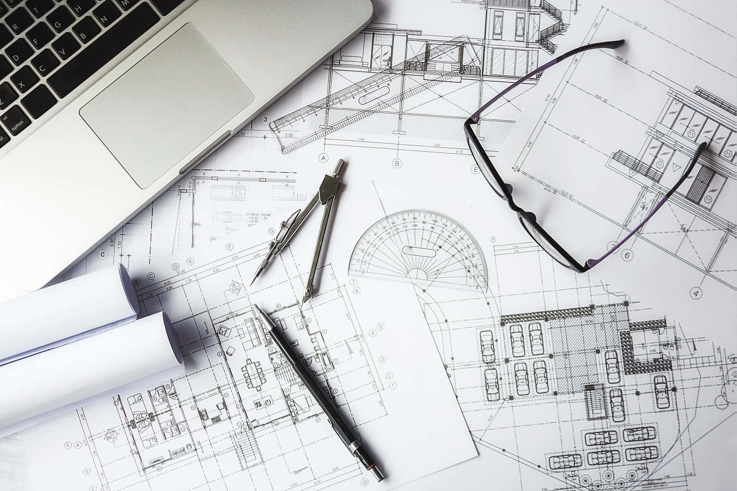 A Laptop, Glasses And Architectural Plans On A Table
