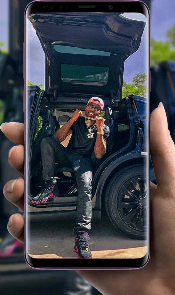 Eineperson Hält Ein Telefon Mit Einem Bild Von Einem Auto. Wallpaper
