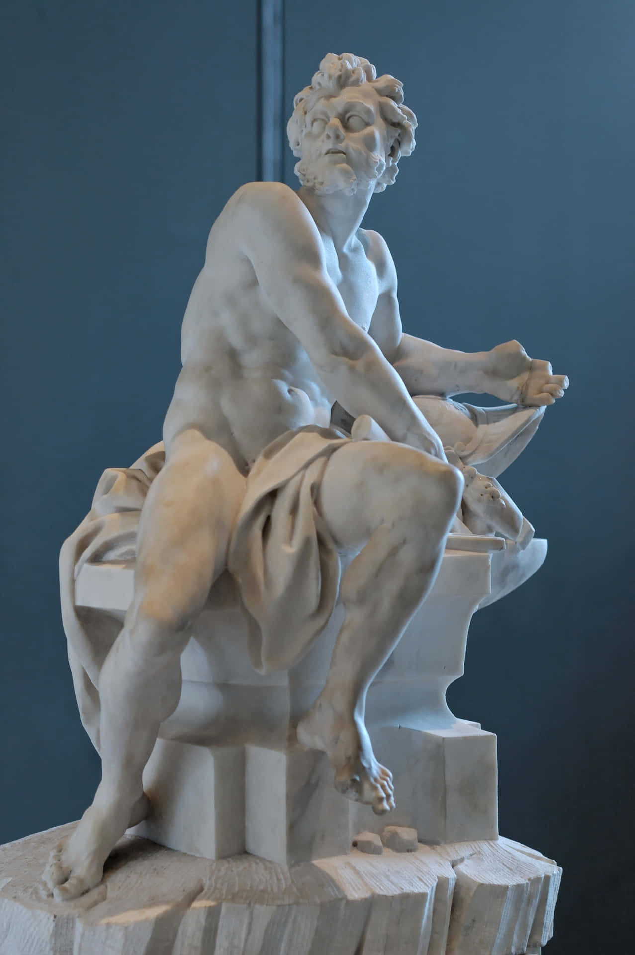 A Statue Of A Man Sitting On A Rock
