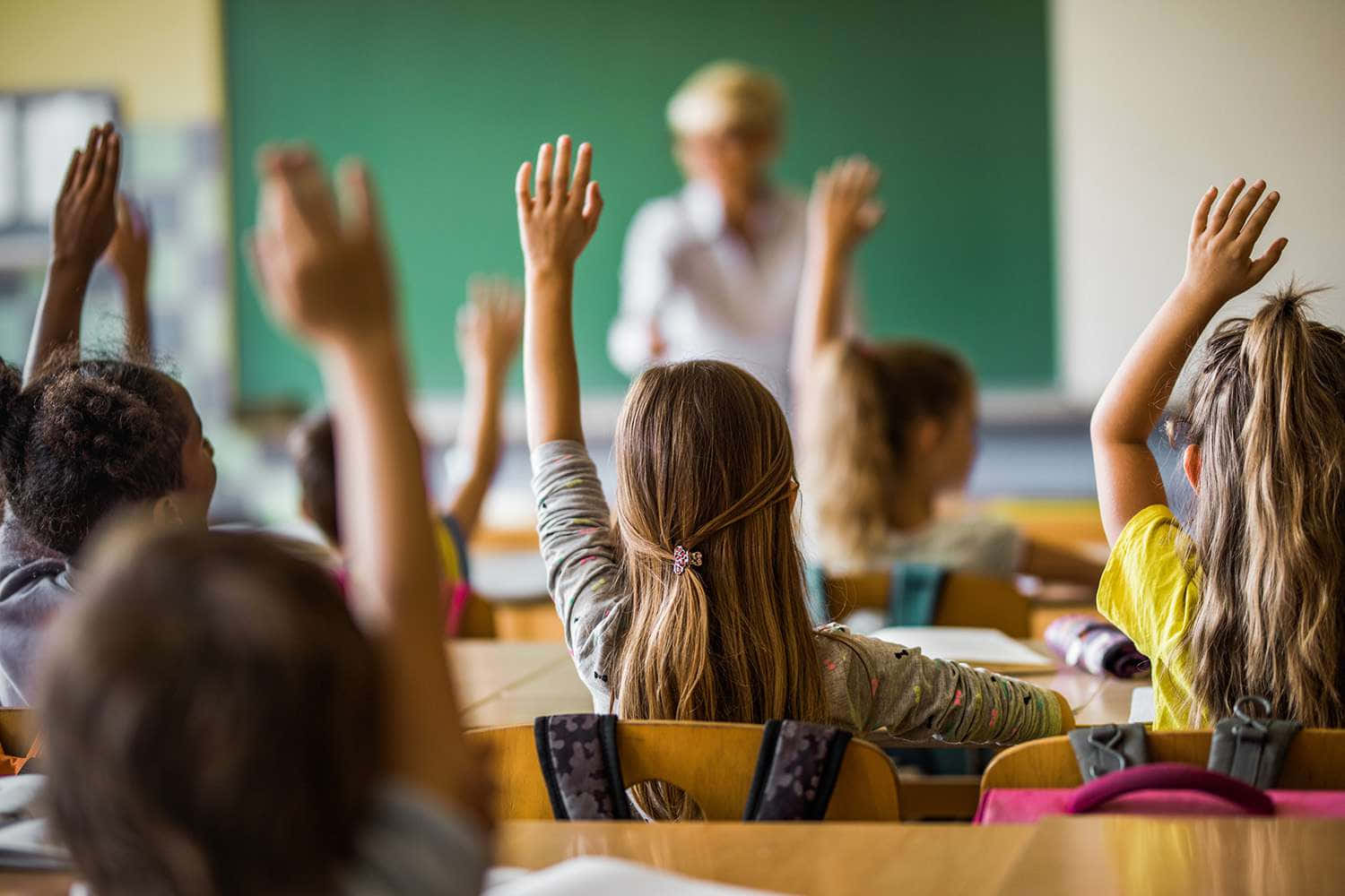 Children Raising Their Hands In A Classroom