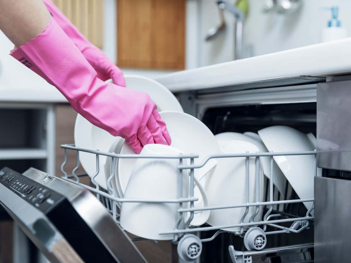 A Woman Is Putting Dishes Into A Dishwasher