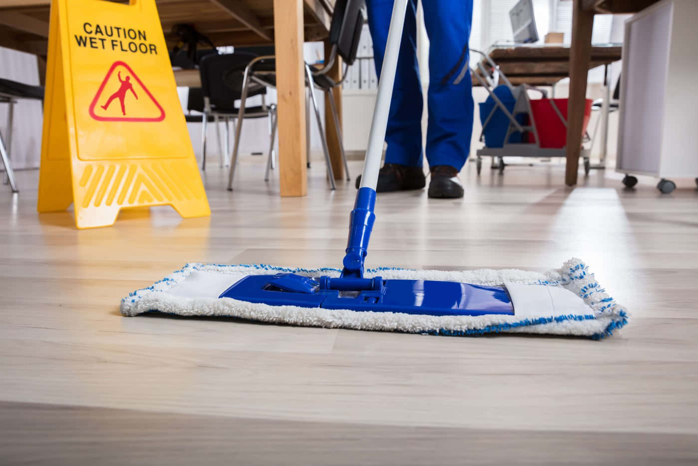 A Man Cleaning A Floor With A Blue Mop