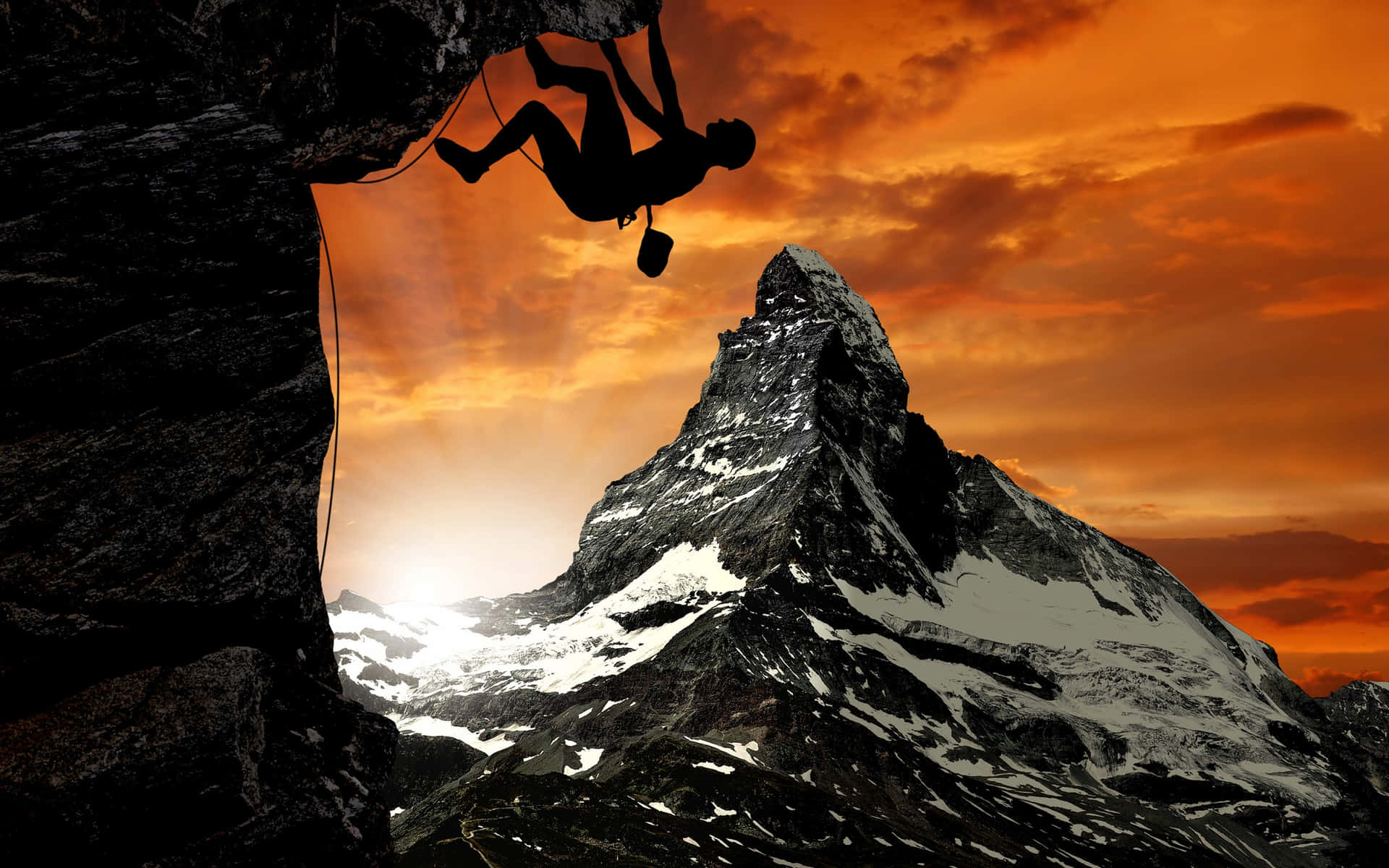 A Man Is Climbing A Mountain At Sunset