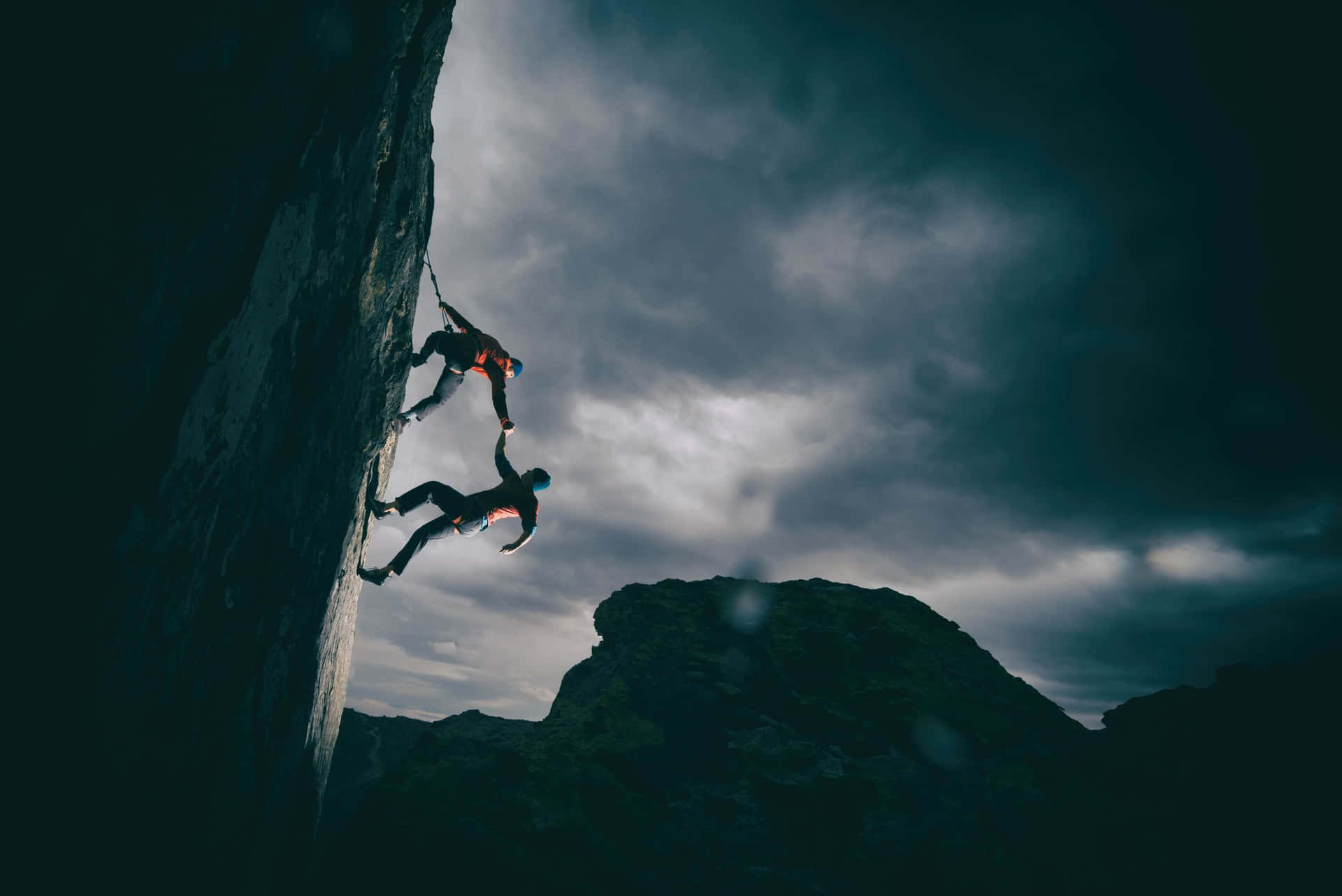 Two People Climbing A Mountain In The Dark