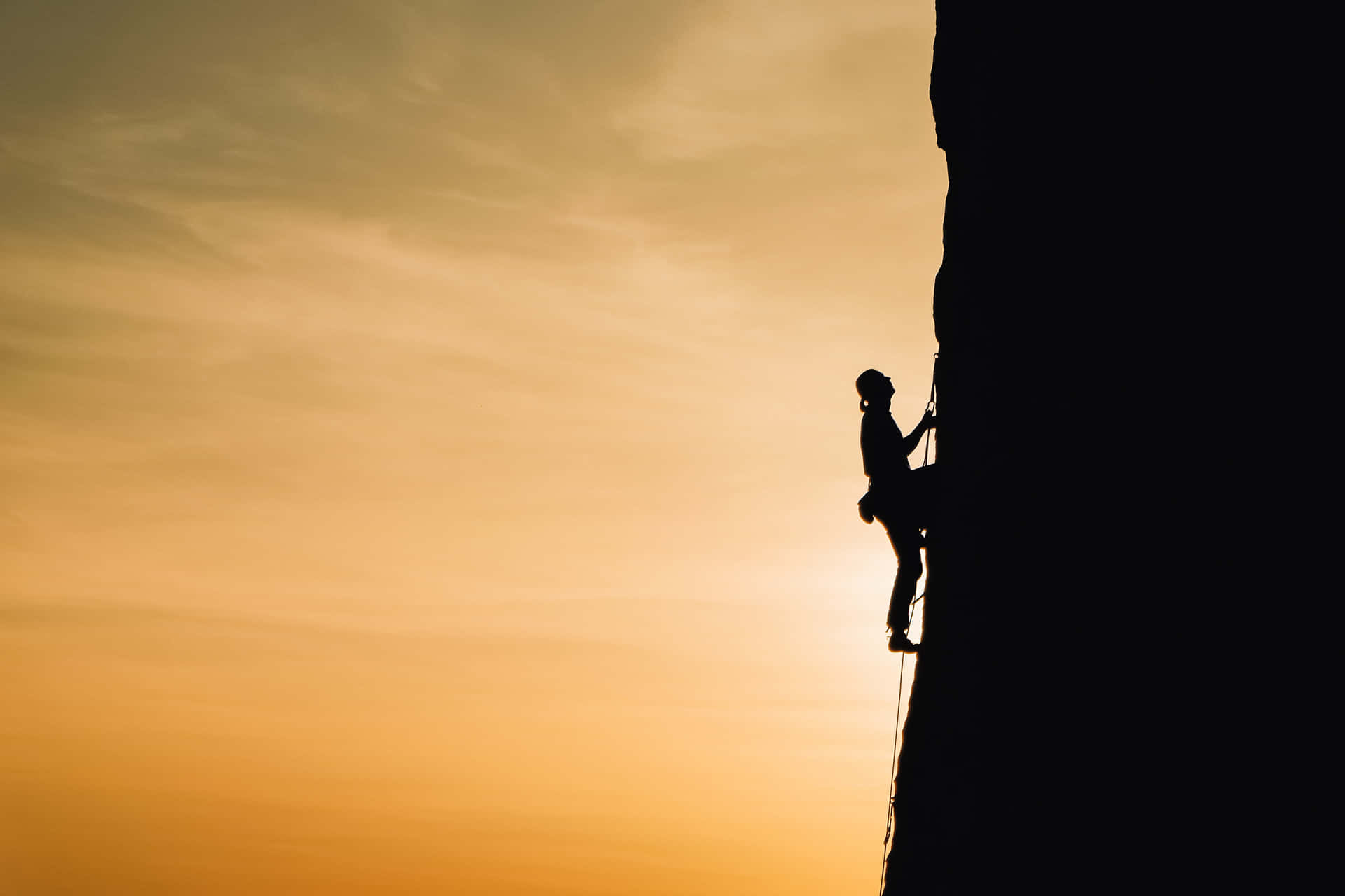 Silhouette Of A Climber Climbing A Rock At Sunset