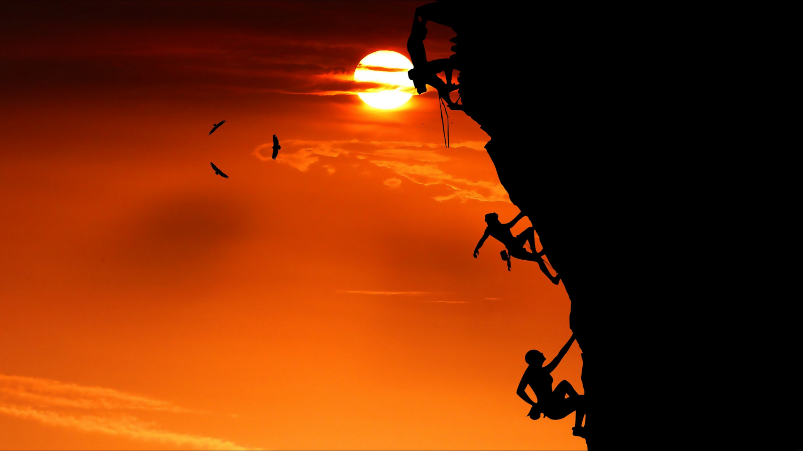Silhouette Of A Man Climbing A Cliff