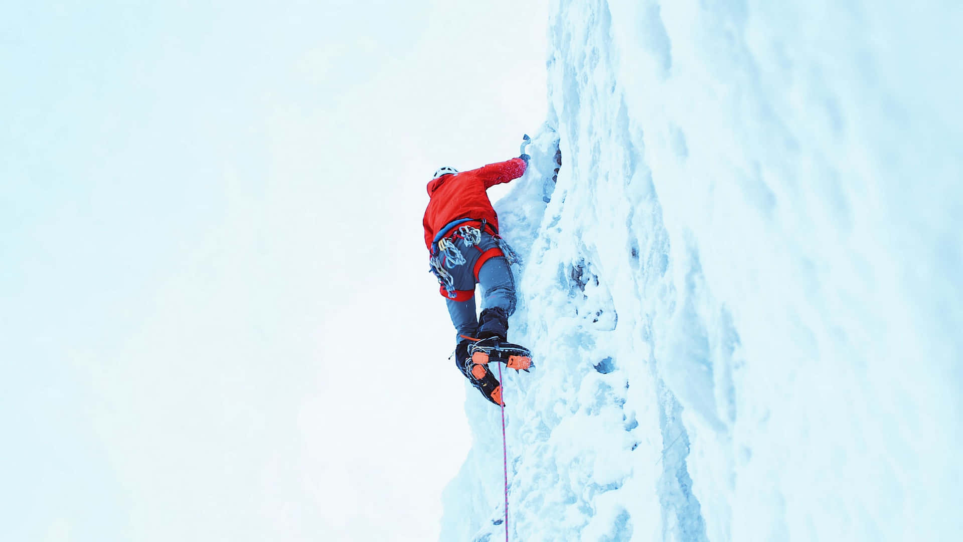 A Man Climbing Up A Snowy Mountain