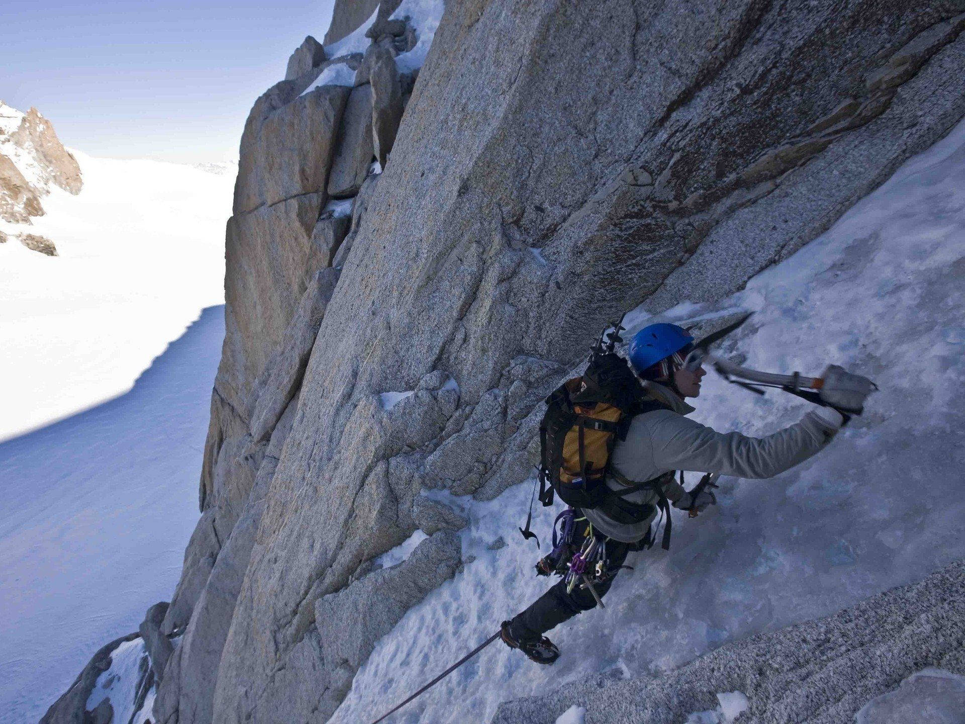 Climbing Mountaineer With Blue Helmet Wallpaper