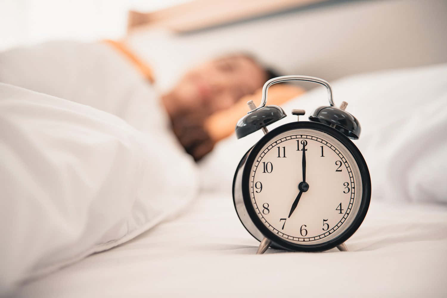 A Woman Is Sleeping In Bed With An Alarm Clock