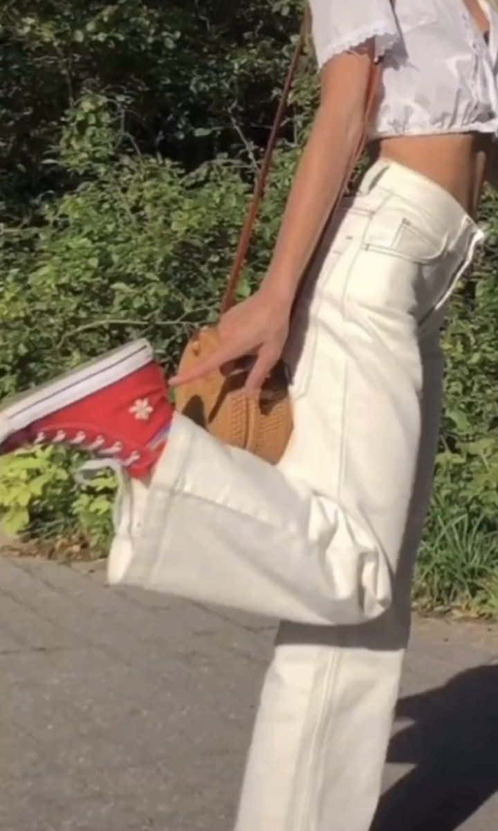 A Woman In White Pants And Red Sneakers