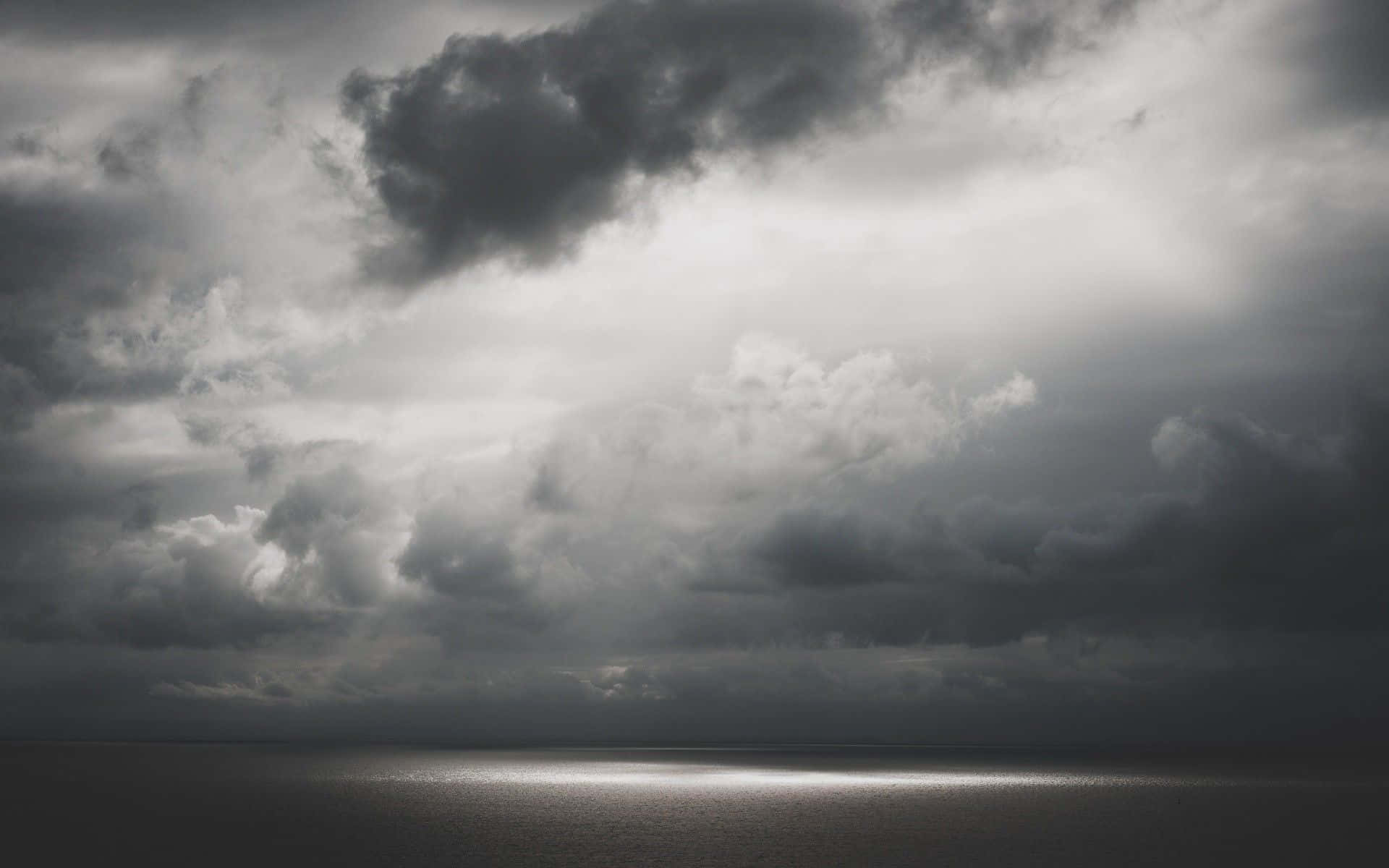 Einschwarz-weißes Foto Eines Dunklen Himmels Mit Einem Licht, Das Hindurchscheint