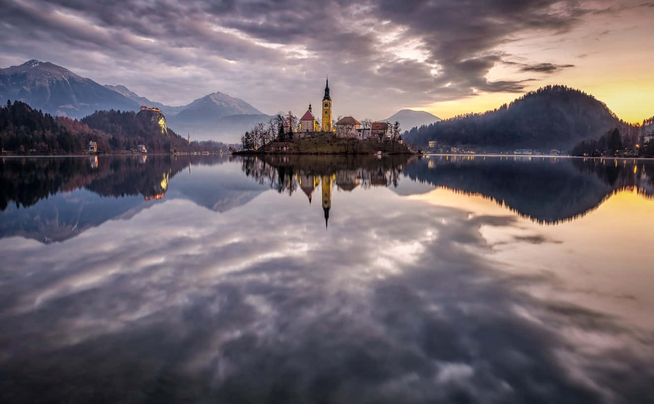 Cloudy Sky Mirrored In Lake Bled Wallpaper
