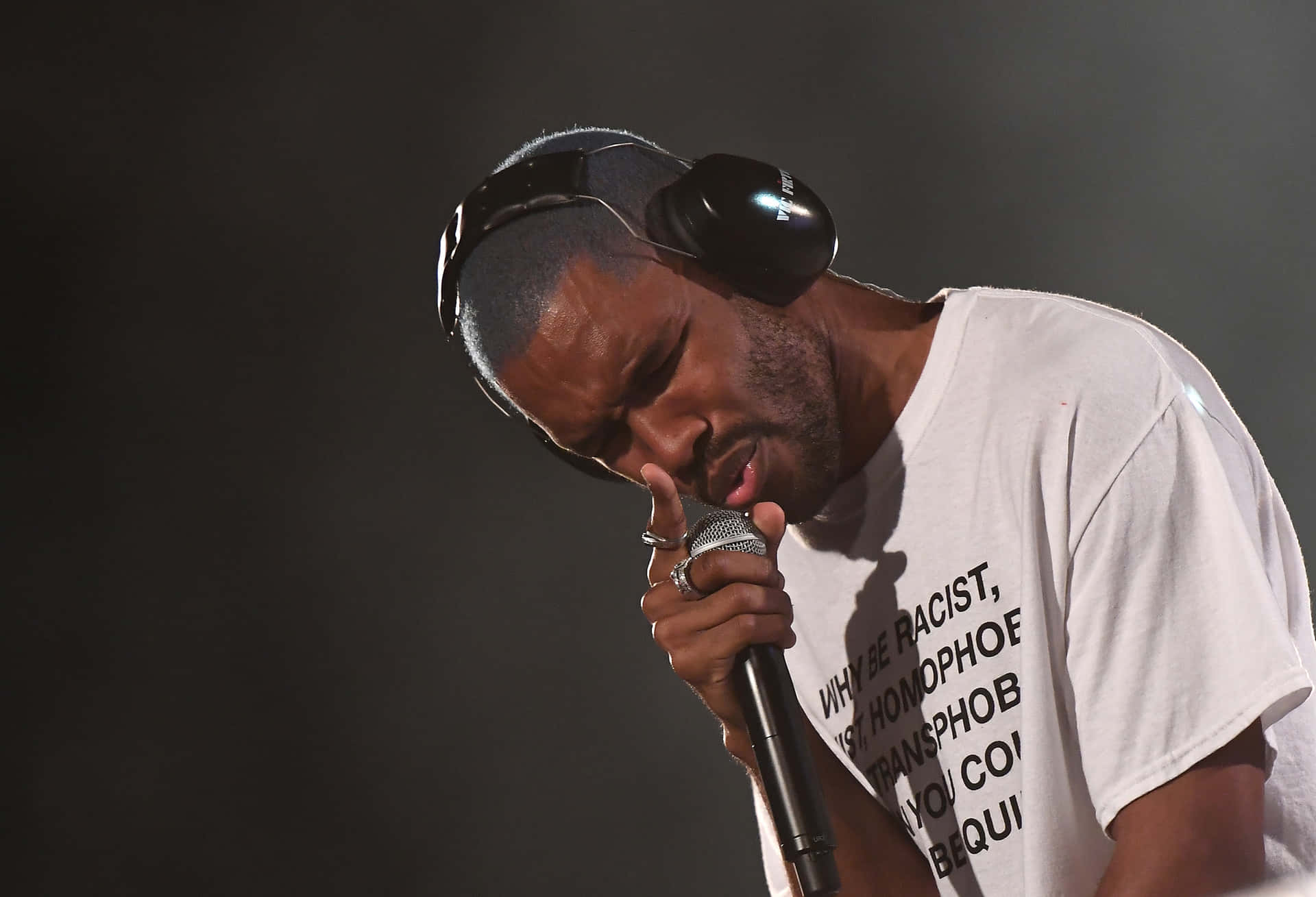 A Man With Headphones Is Holding A Microphone