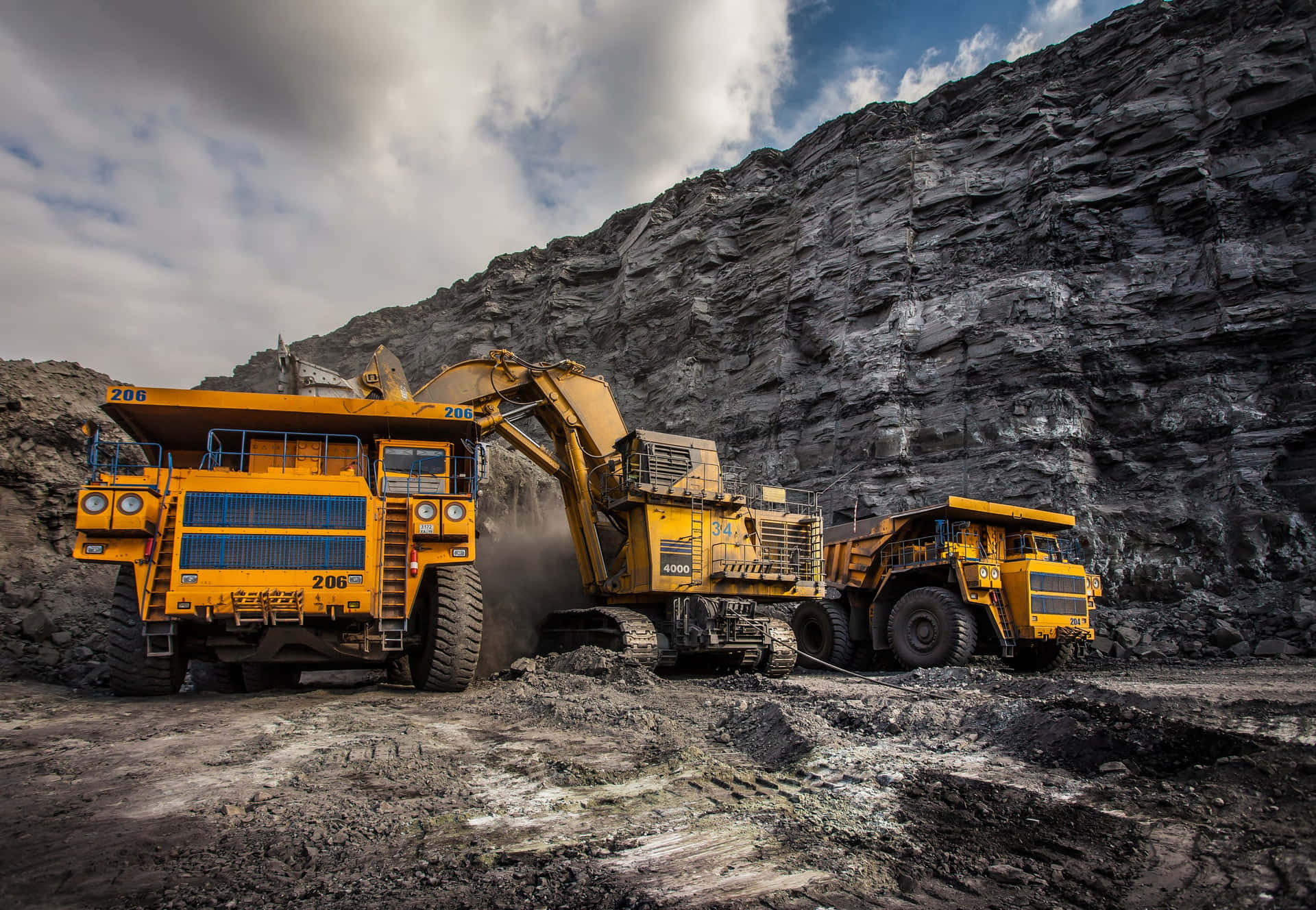 Two Large Trucks Are Parked In A Coal Mine
