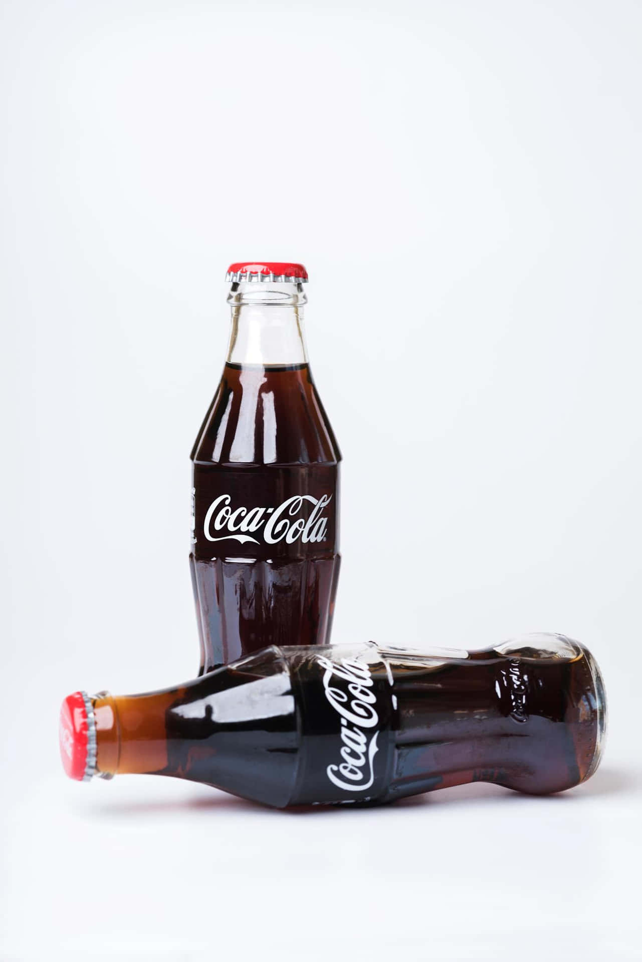 Tvåcoca-cola-flaskor På En Vit Bakgrund