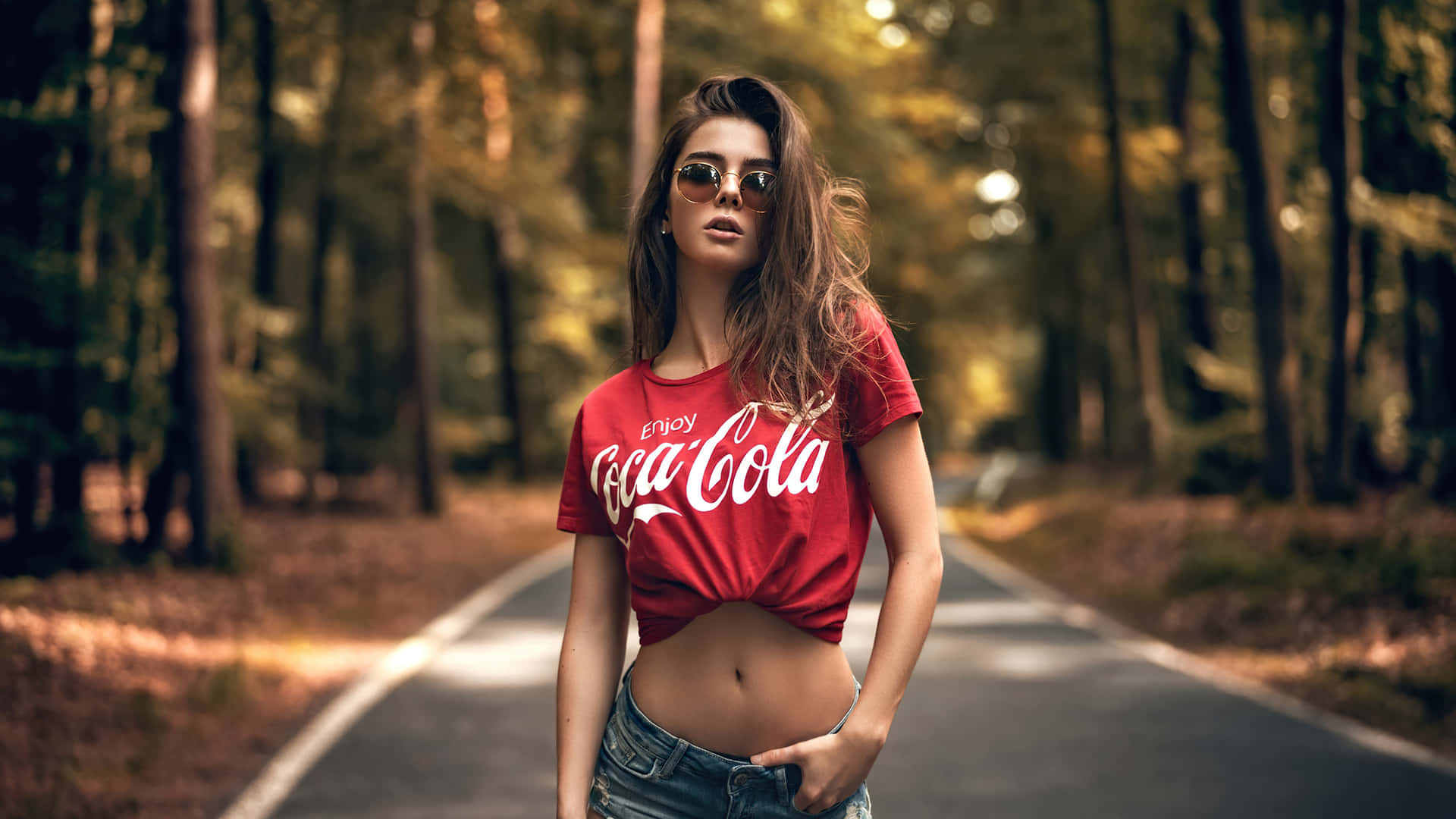 Umamulher Com Uma Camiseta Vermelha Da Coca Cola Em Pé Em Uma Estrada. Papel de Parede