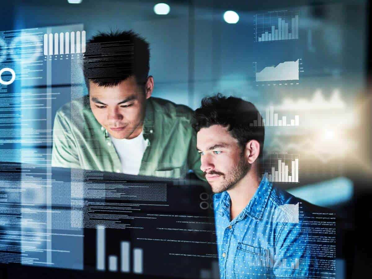Two Men Looking At A Computer Screen With Graphs
