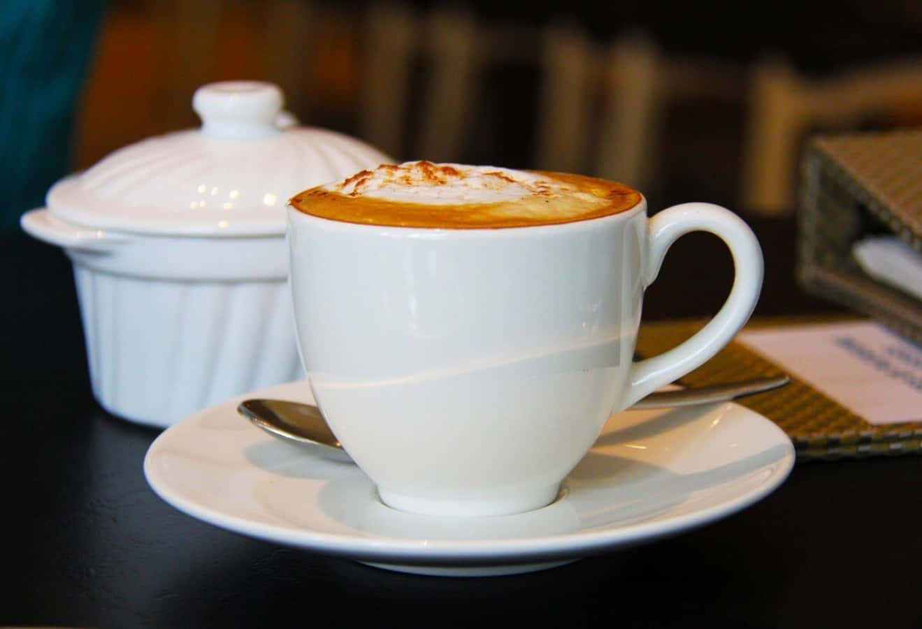 A White Cup Of Coffee With A Saucer On A Table